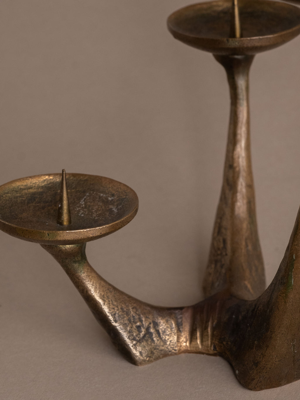 Sculptural German bronze candleholder shown in full profile with a rough textured surface.
