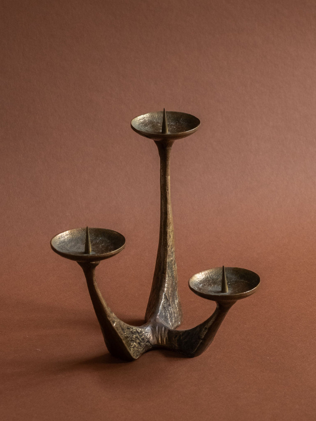 Detail of a candle pricket and textured bronze surface on the vintage three-arm candleholder.
