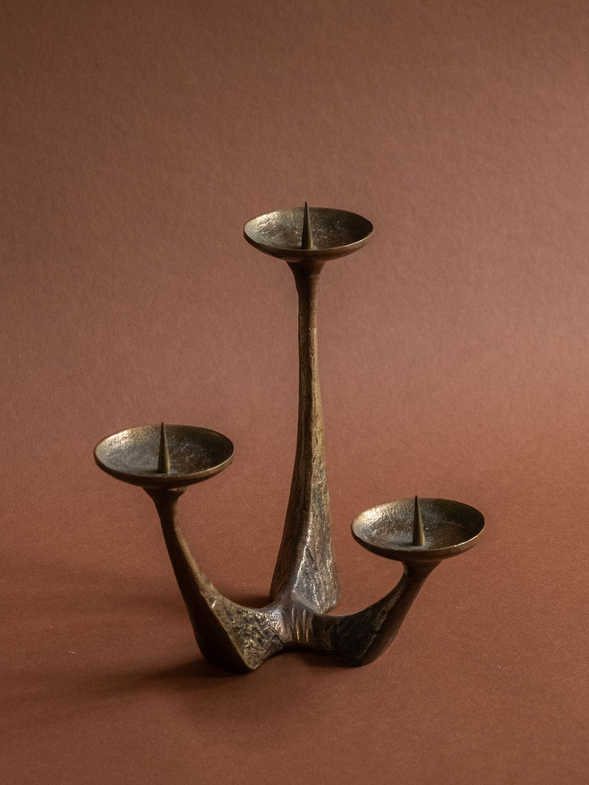 Detail of a candle pricket and textured bronze surface on the vintage three-arm candleholder.