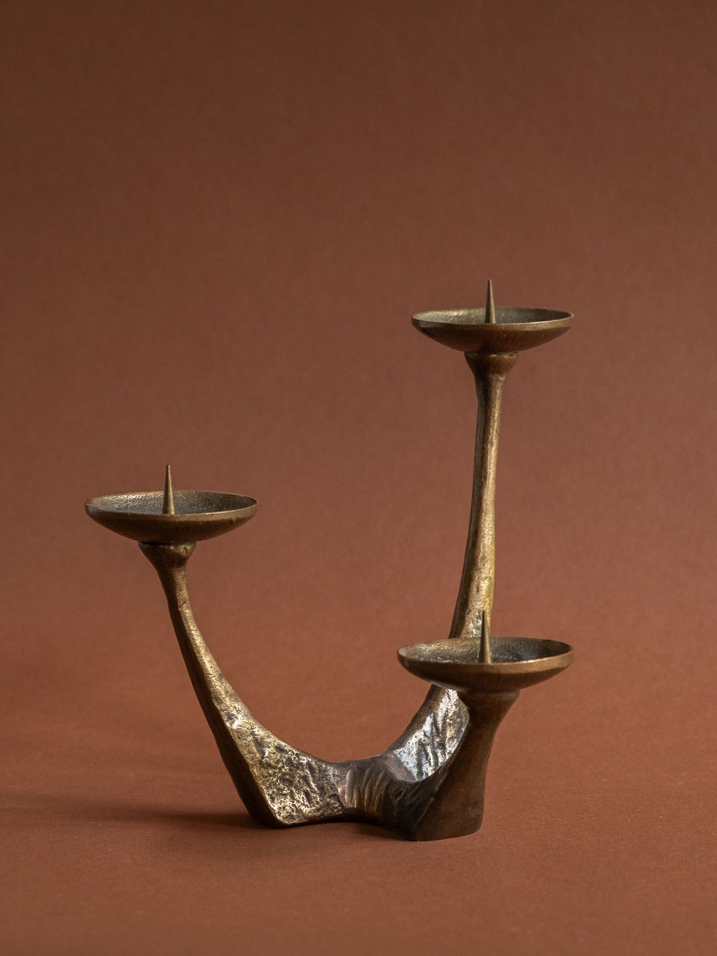 Close view of the branching bronze body and aged brown-gold patina of the candleholder.