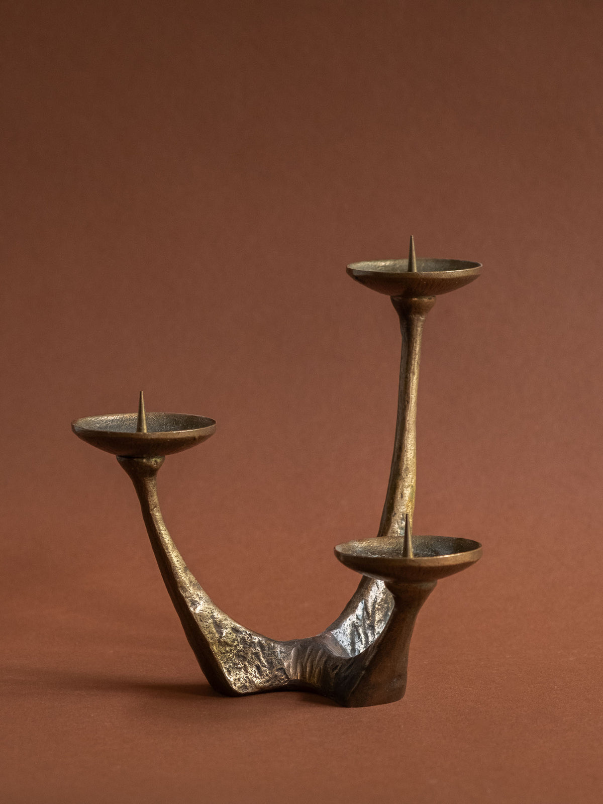 Close view of the branching bronze body and aged brown-gold patina of the candleholder.