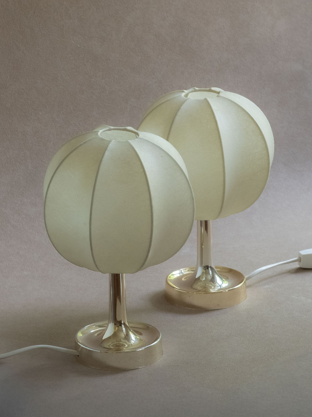 Single Goldkant Salbo cocoon table lamp lit against a neutral wall, showing the soft glow of the off-white ribbed shade.