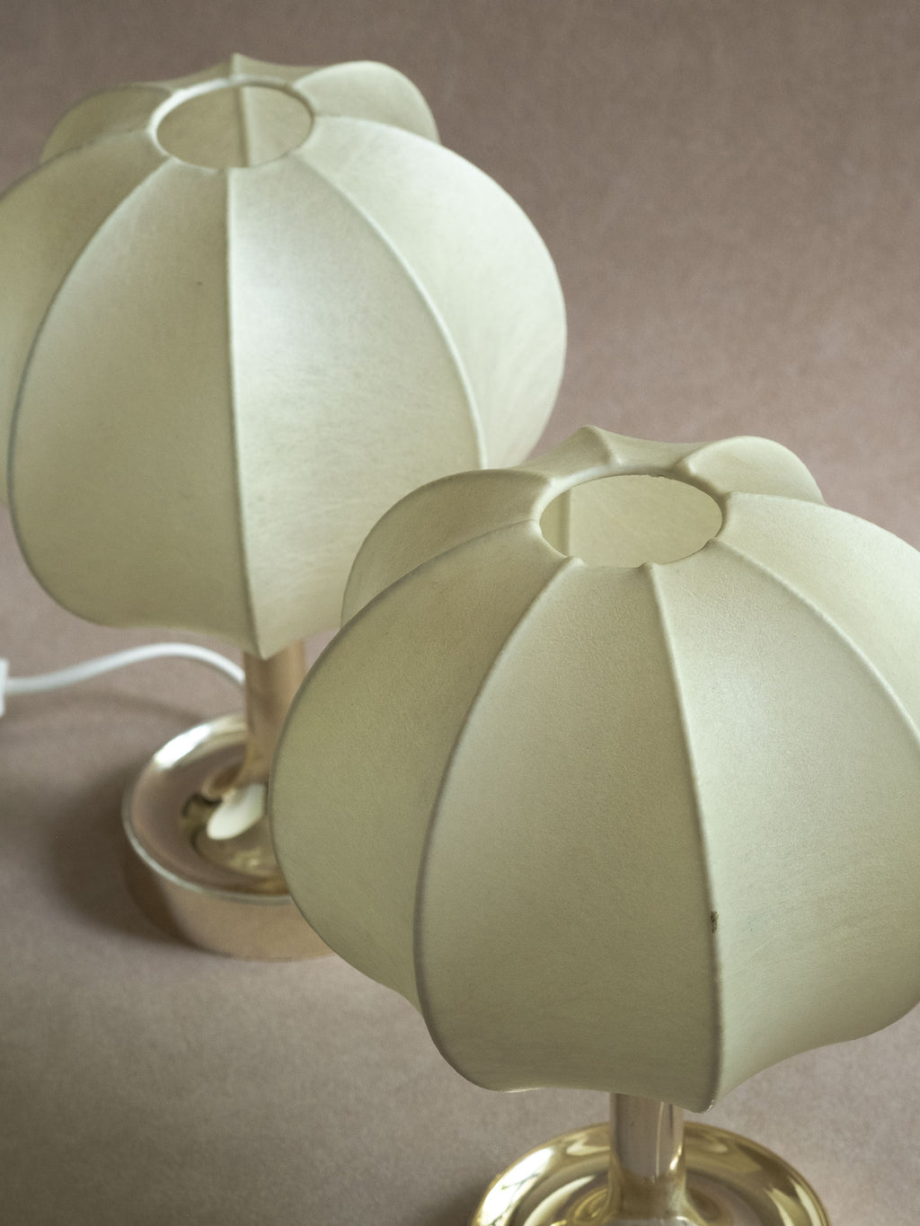 Pair of Goldkant Salbo cocoon table lamps with off-white rounded shades and reflective bases against a neutral wall.
