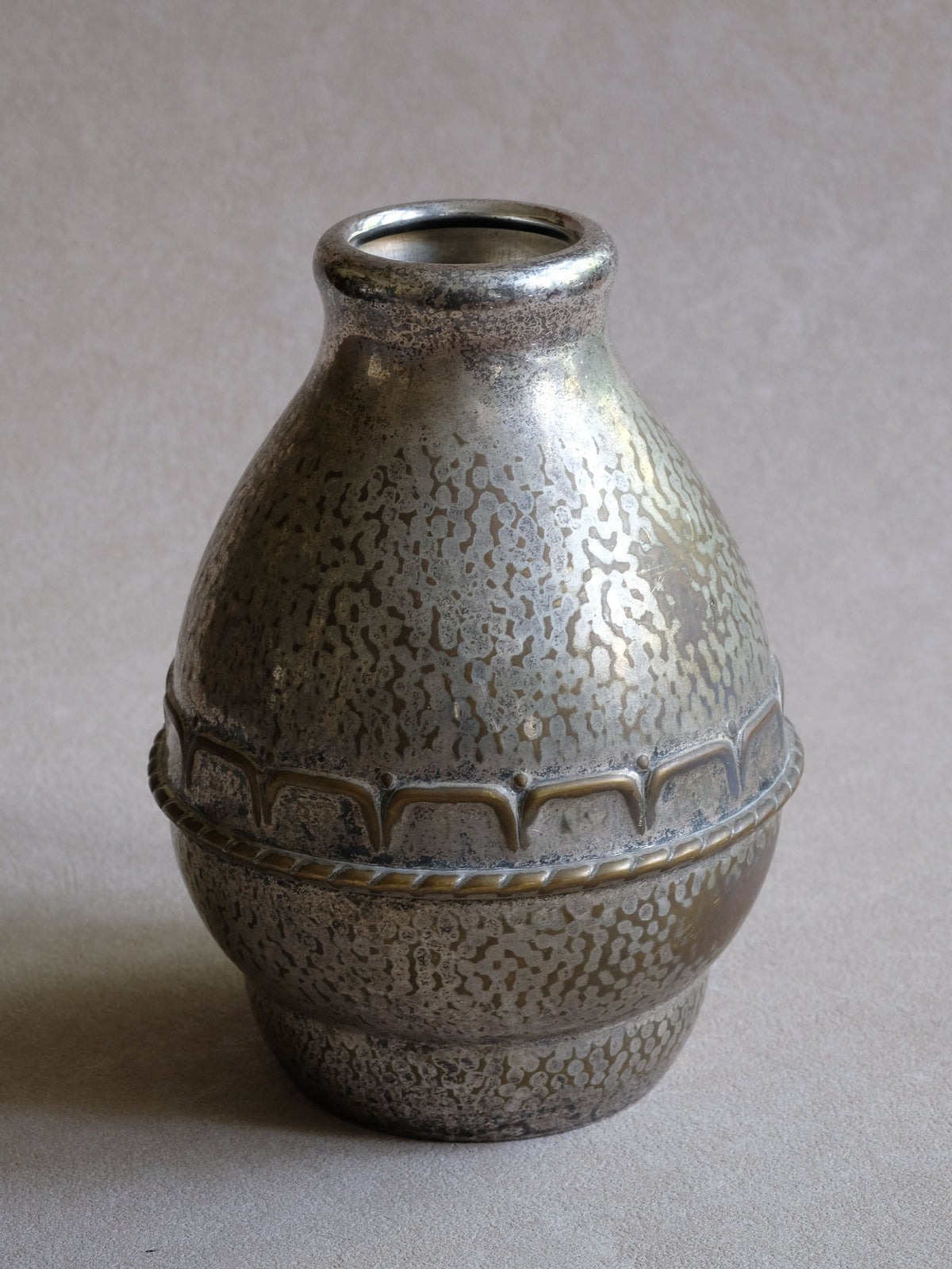 Angled view of the HAGS vase showing its narrow opening, rounded body and hammered silver-plated surface.