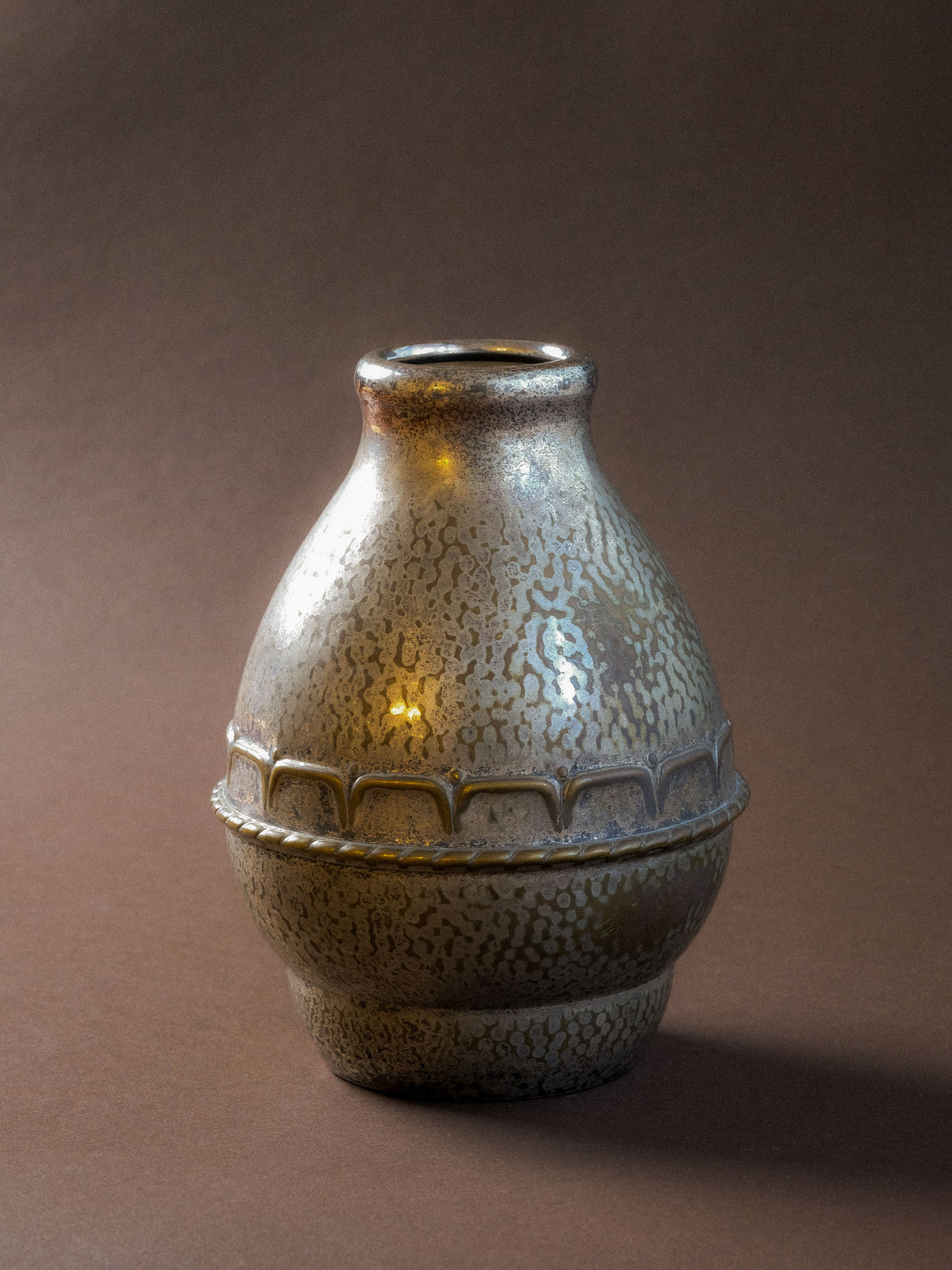 Angled view of the HAGS vase showing its narrow opening, rounded body and hammered silver-plated surface.
