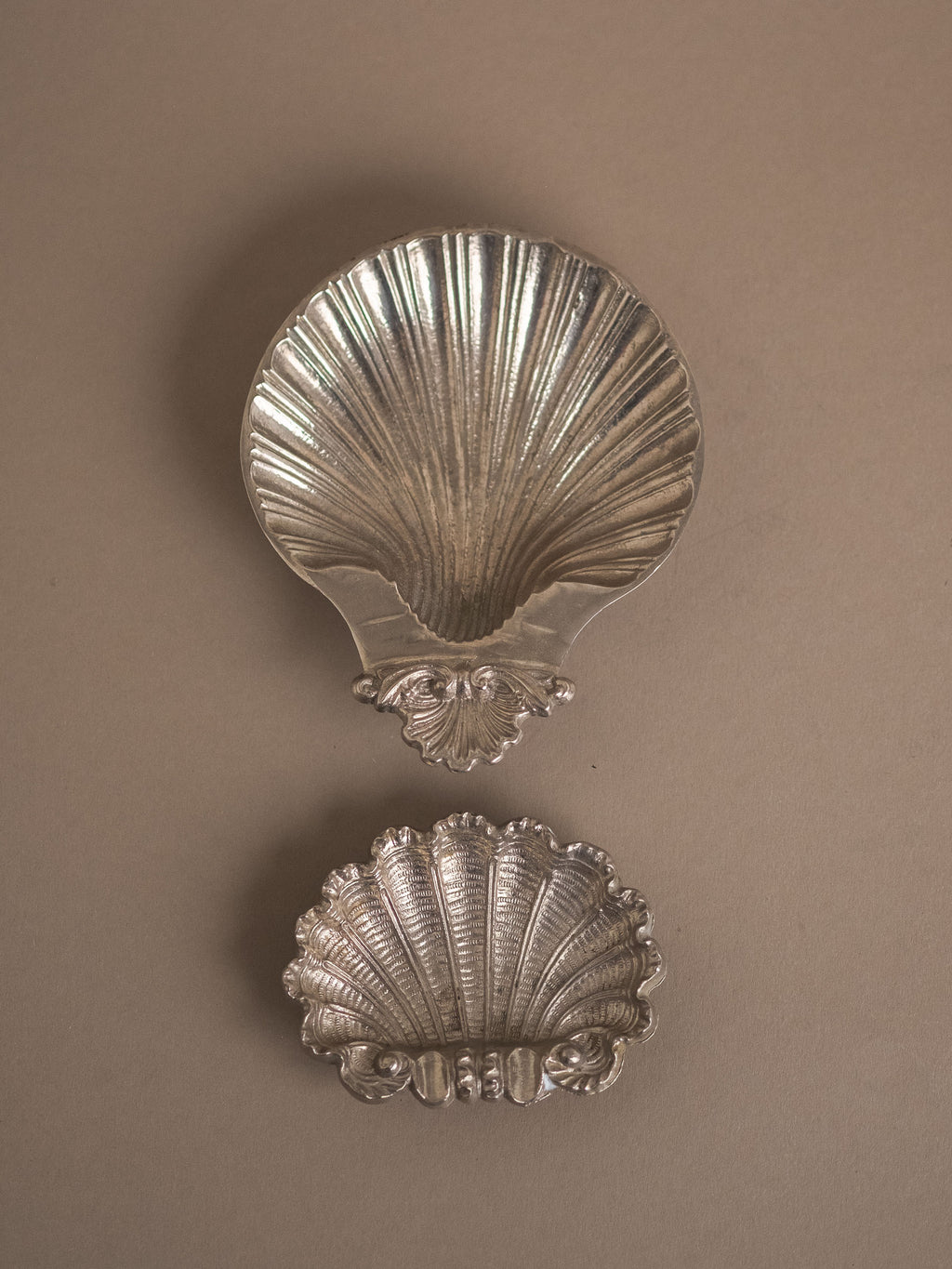 Hans Baier silver-plated scallop shell dish photographed above another shell-form dish on a neutral background, showing both pieces in full view.