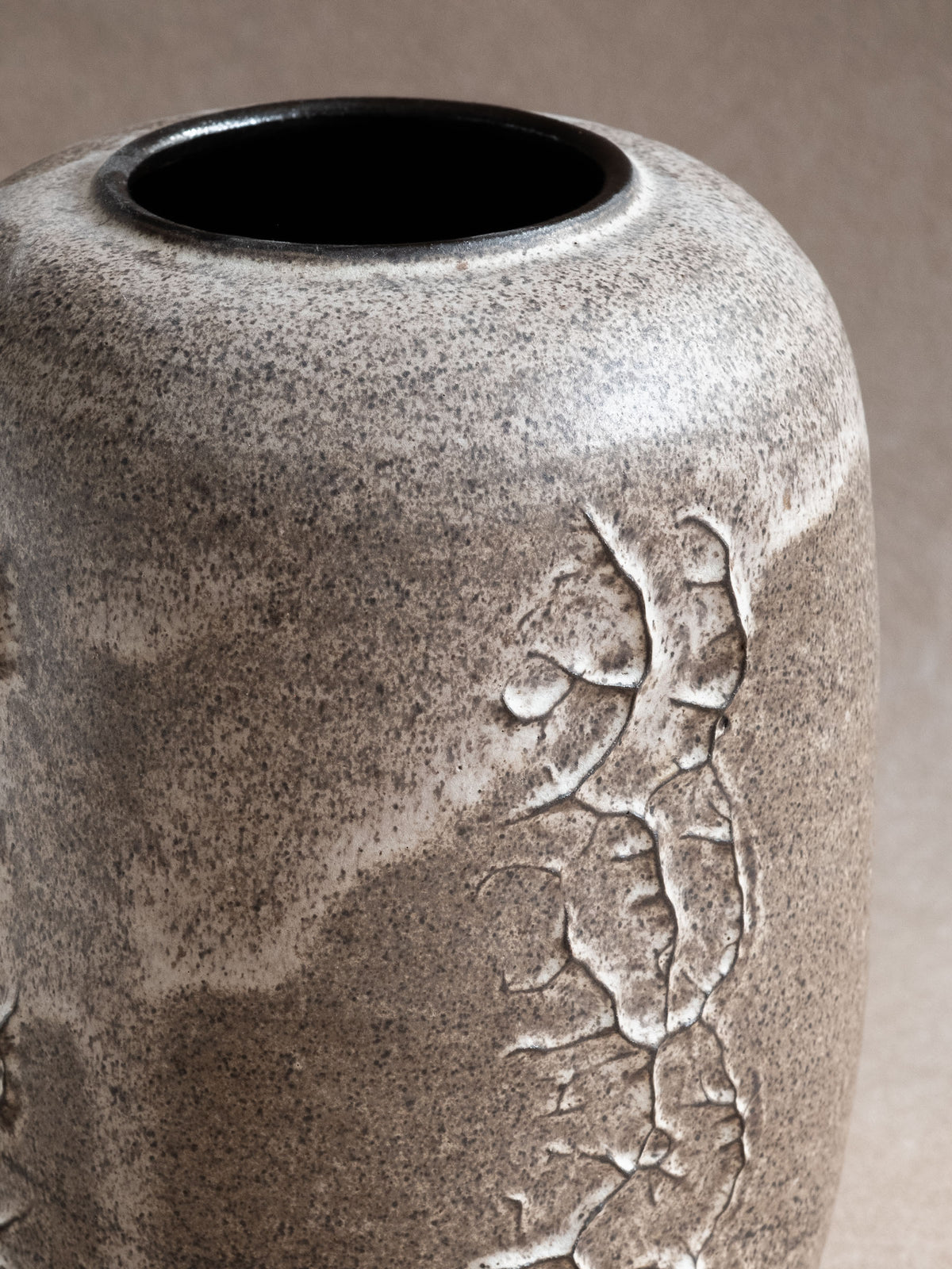 Side view highlighting the muted grey-taupe ceramic body and raised white linear motif.