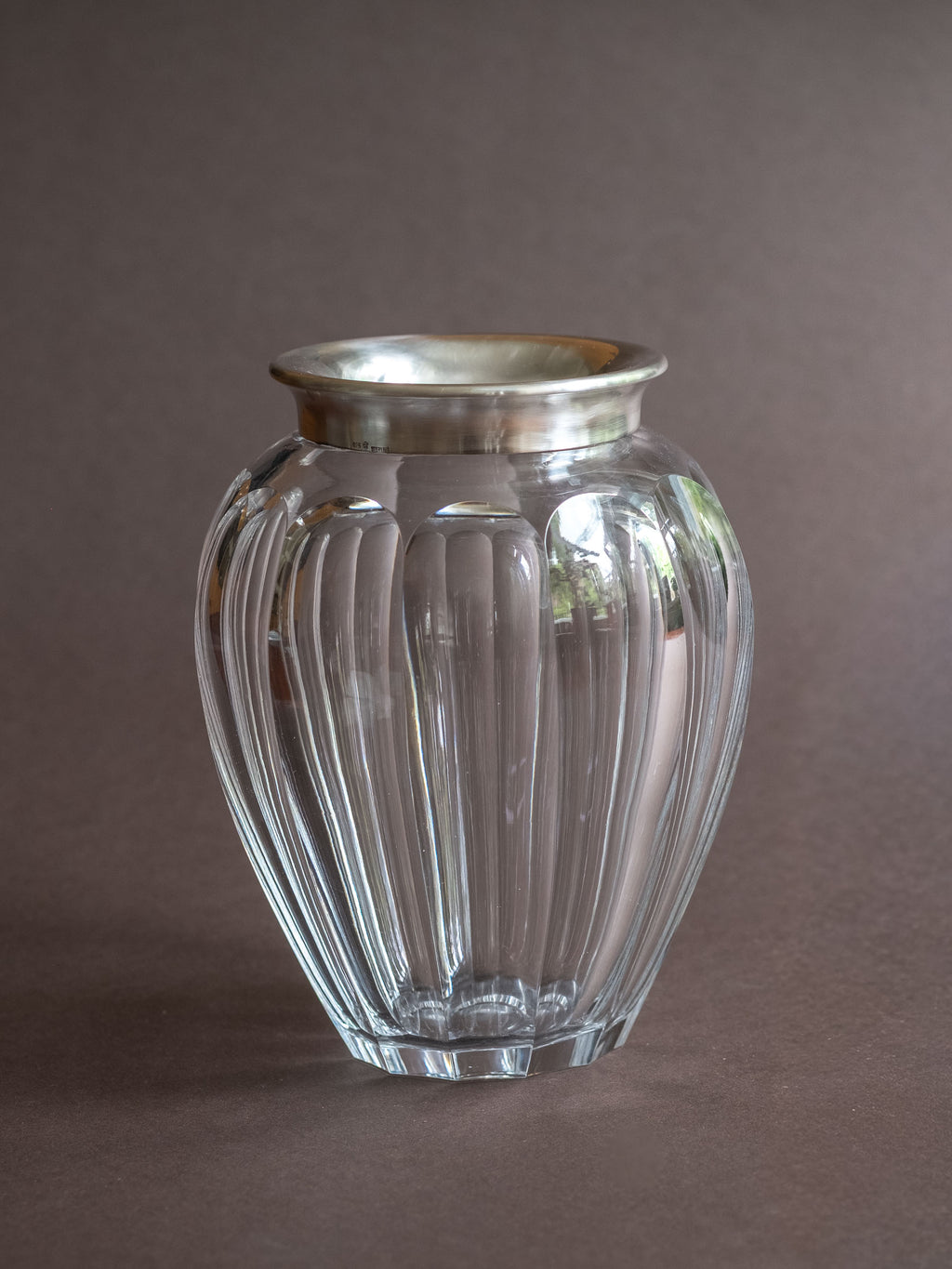 Hermann Bauer crystal vase with sterling silver rim shown from the front, with a rounded cut glass body on a dark background.
