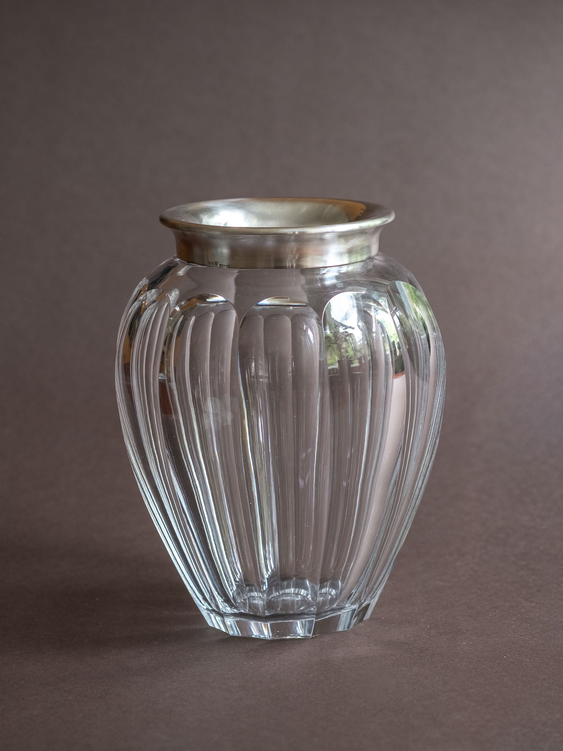 Hermann Bauer crystal vase with sterling silver rim shown from the front, with a rounded cut glass body on a dark background.
