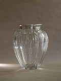 Crystal vase with sterling silver rim shown against a neutral background, with the cut glass body reflecting light.
