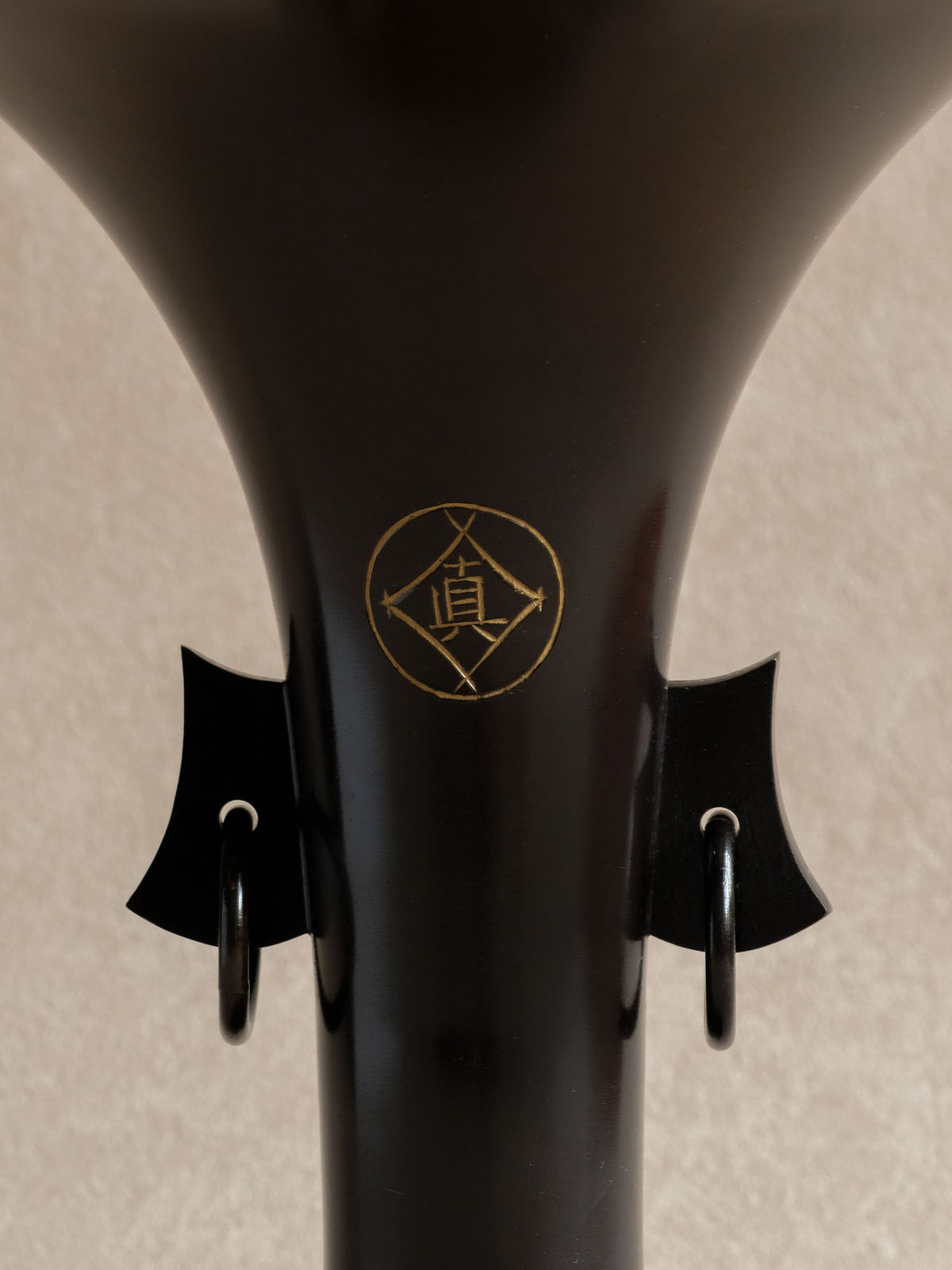 Gold-toned 真 emblem above paired hanging rings on the Hirose Yūdō bronze Zuishō vase.