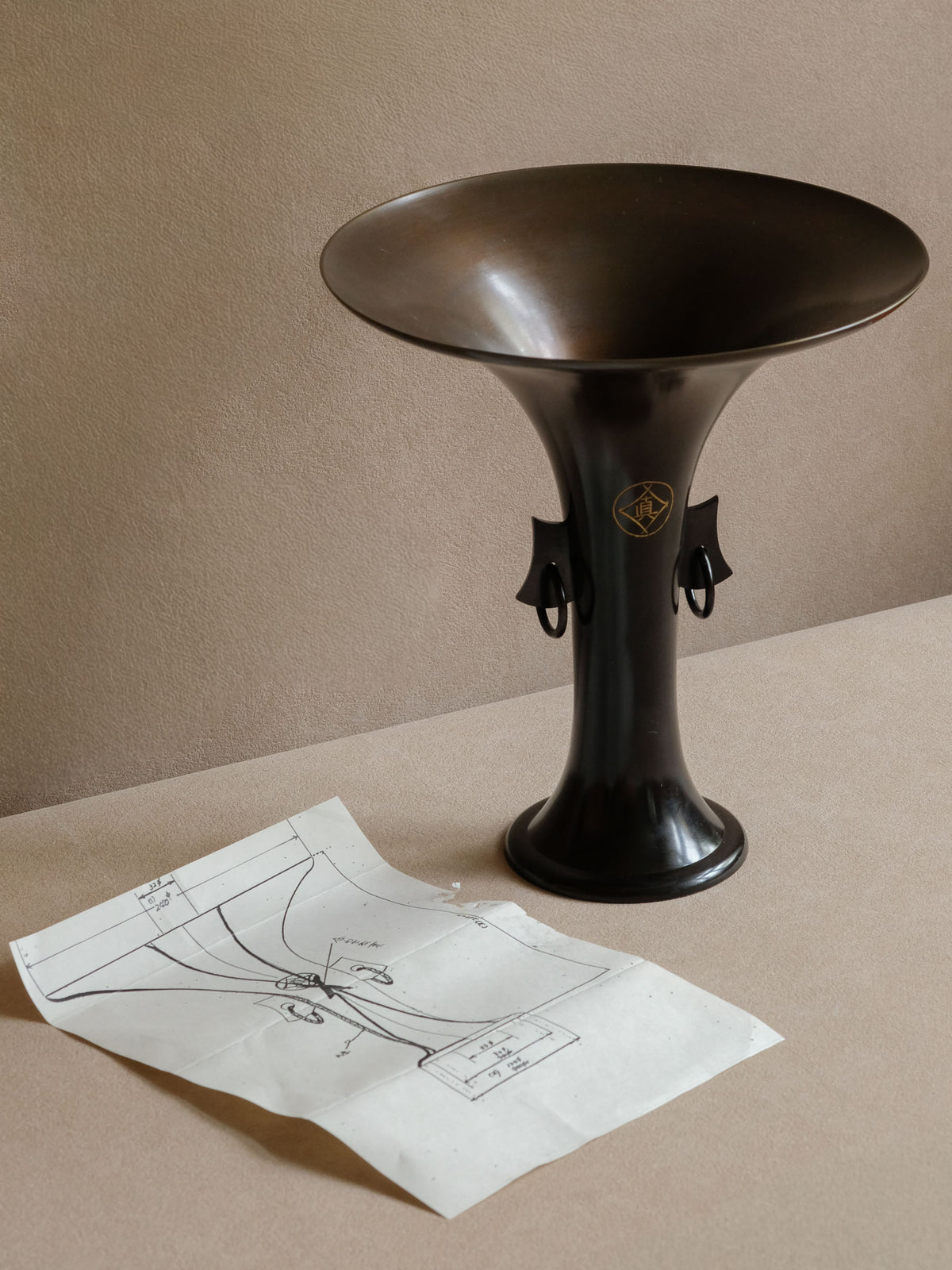 Side profile of Hirose Yūdō bronze flower vase with ring handle and architectural taper.