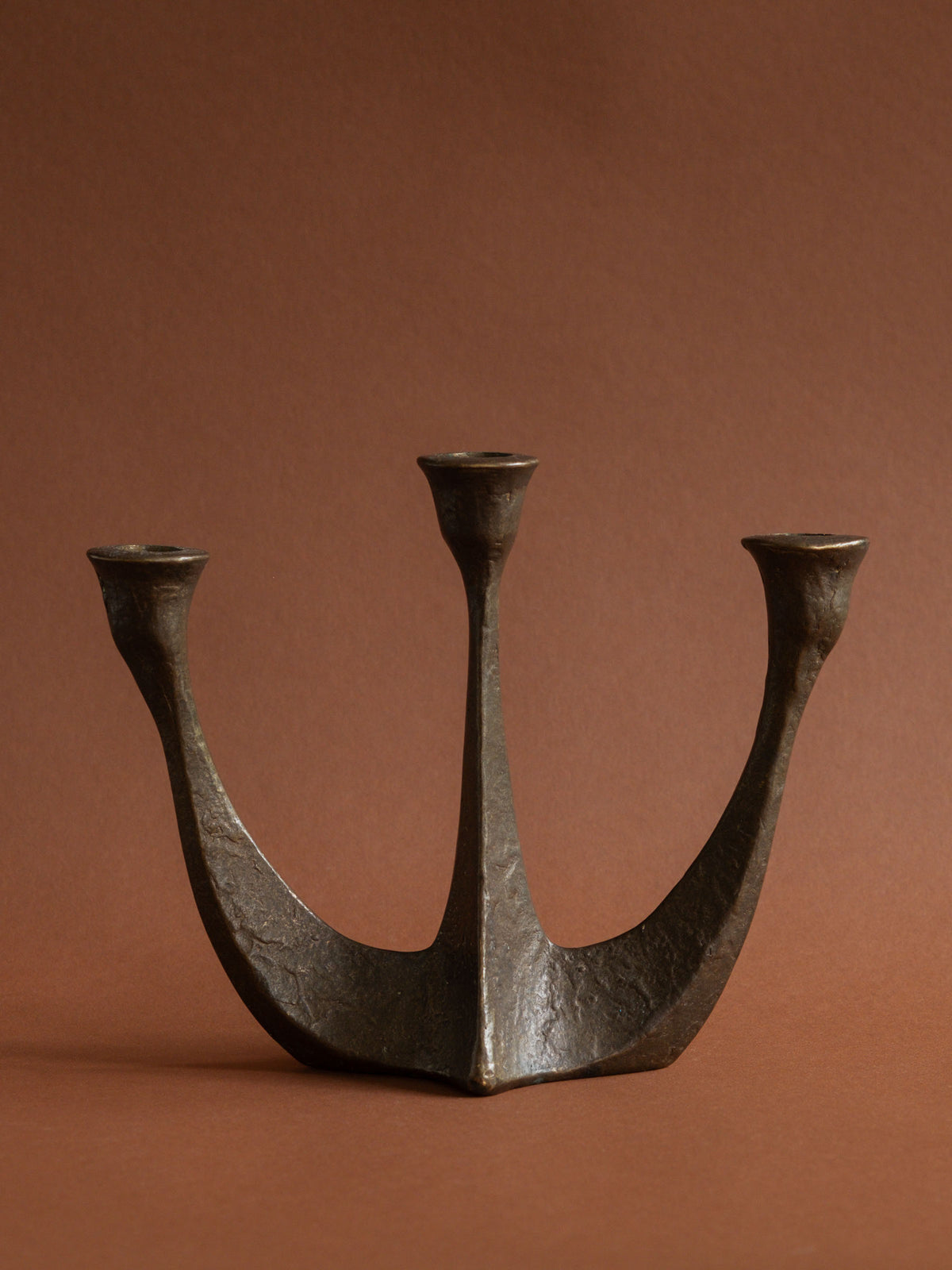 Detail of the textured bronze surface and aged brown-gold patina on the Dalbeck candleholder.