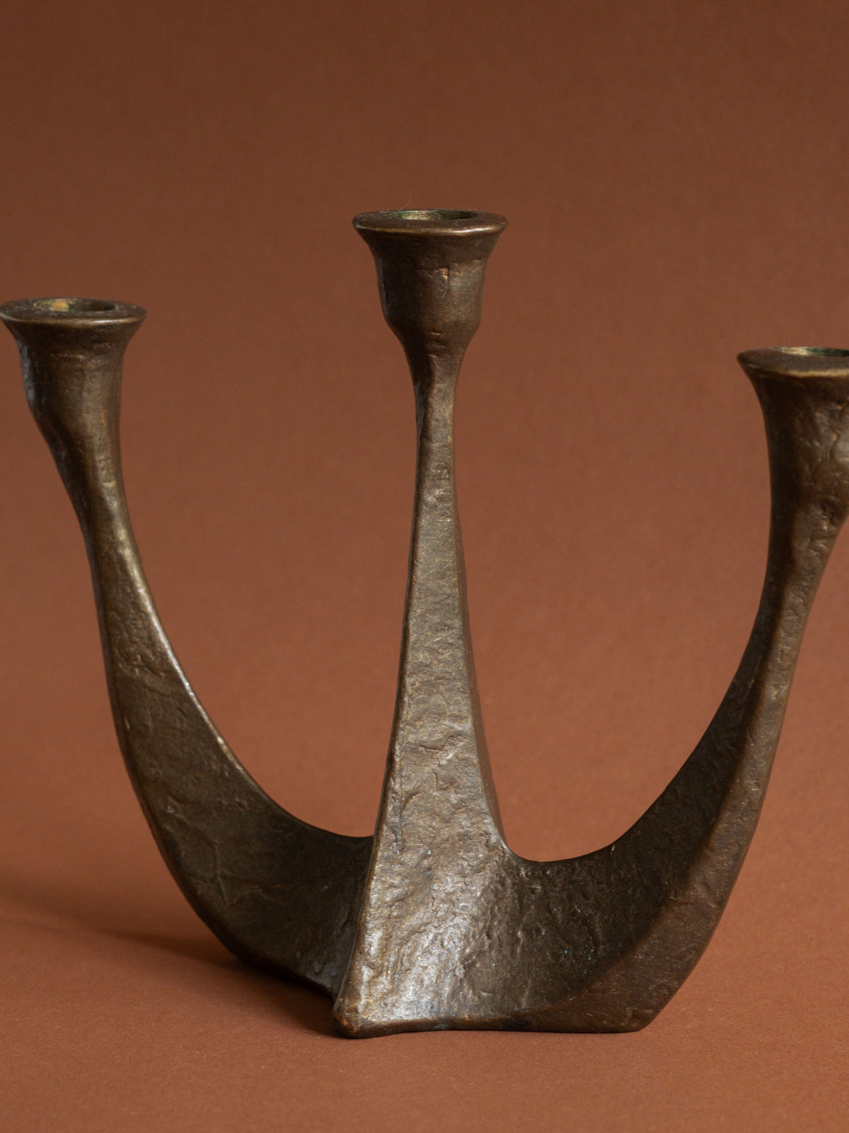 Alternate view of the Horst Dalbeck three-arm bronze candleholder and its low sculptural base.