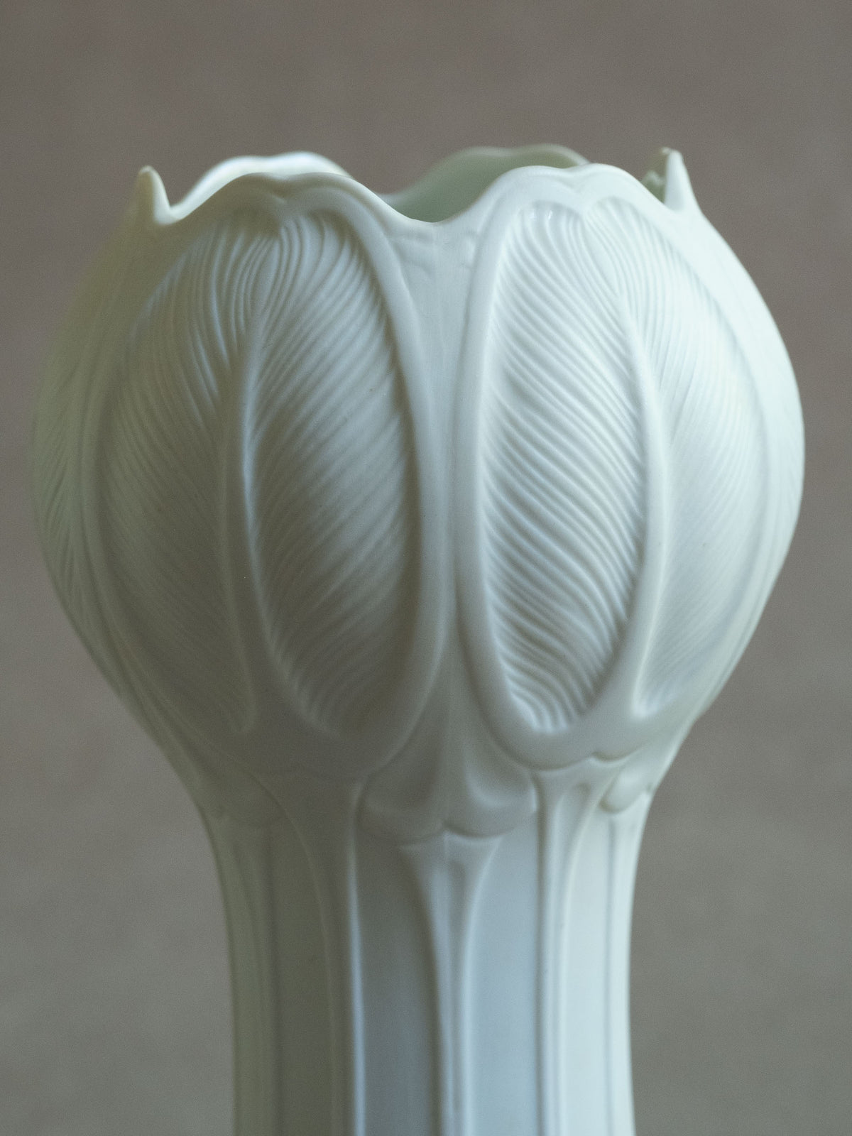 Detail of the sculptural tulip form and overlapping white porcelain leaf relief on the Hans Achtziger Hutschenreuther vase.