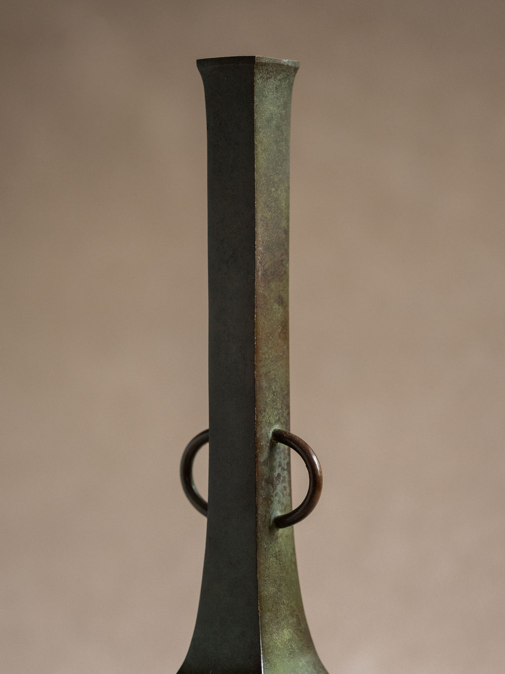 Close-up of the long square neck and ring handles of a patinated Japanese copper-alloy hanaire vase.