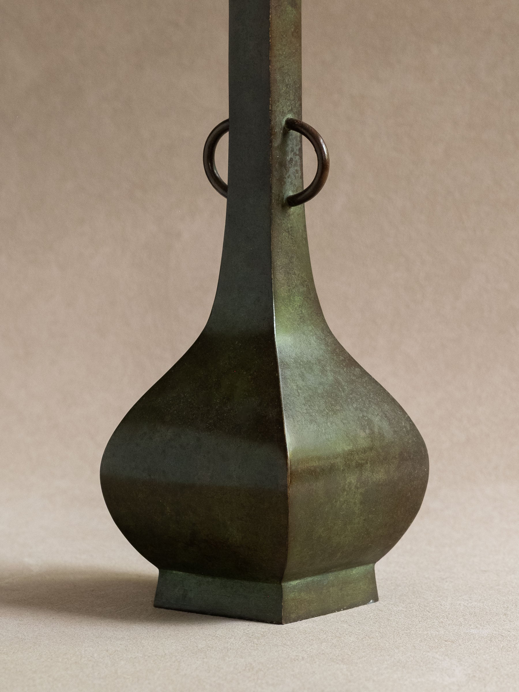 Close-up of the four-sided lower body and ring handles of a green-brown Japanese copper-alloy hanaire vase.