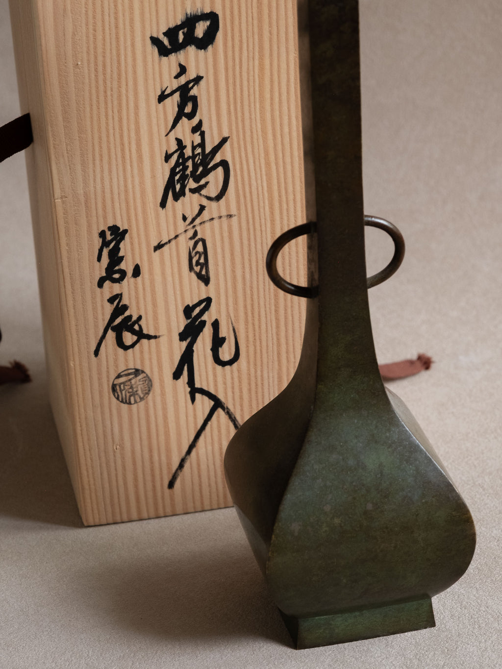 Japanese copper-alloy hanaire vase with square neck, ring handles, and original wooden storage box.