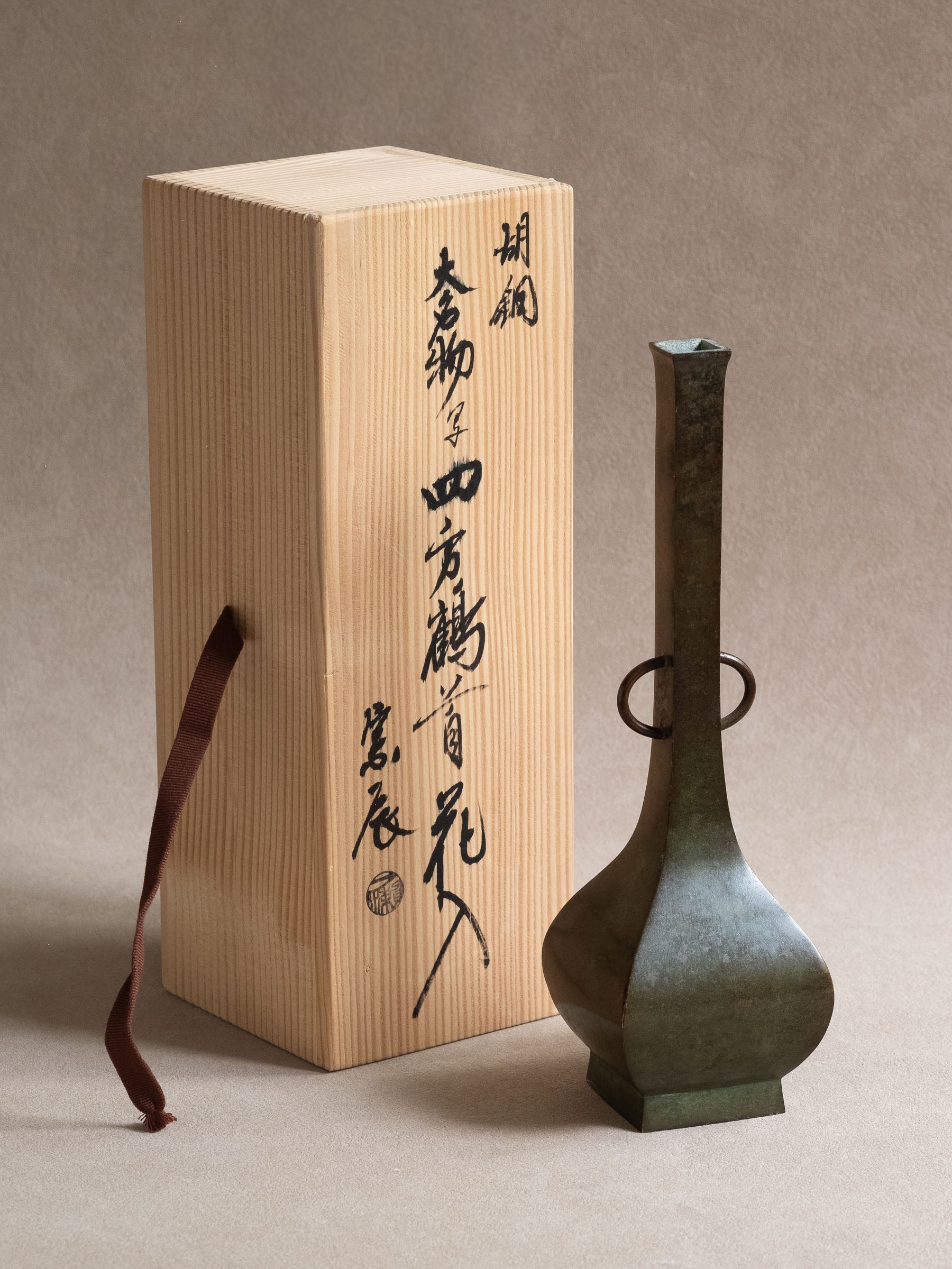 Japanese copper-alloy hanaire vase shown beside its original inscribed wooden box and paper leaflet.
