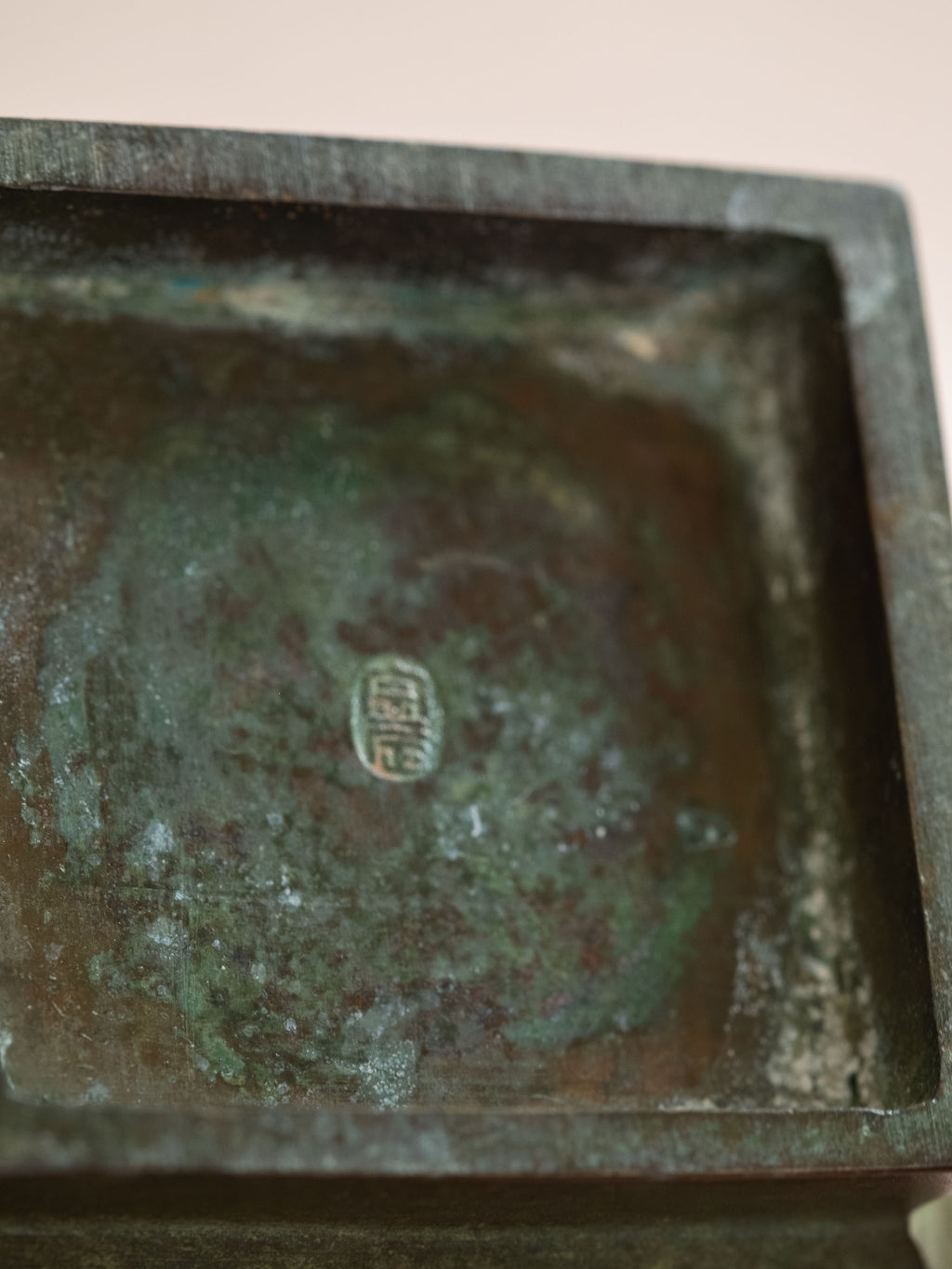 Close-up of the signed mark on a green-brown patinated Japanese copper-alloy hanaire vase.