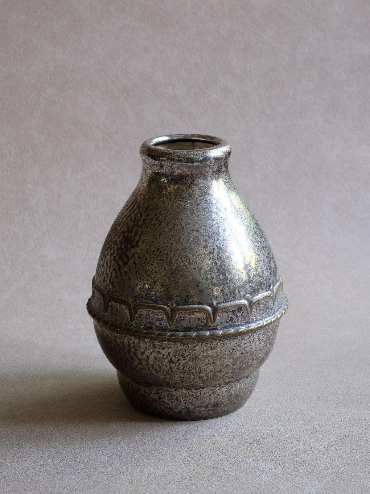 Close view of the aged HAGS silver-plated vase with mottled wear, small dents and raised decorative band.