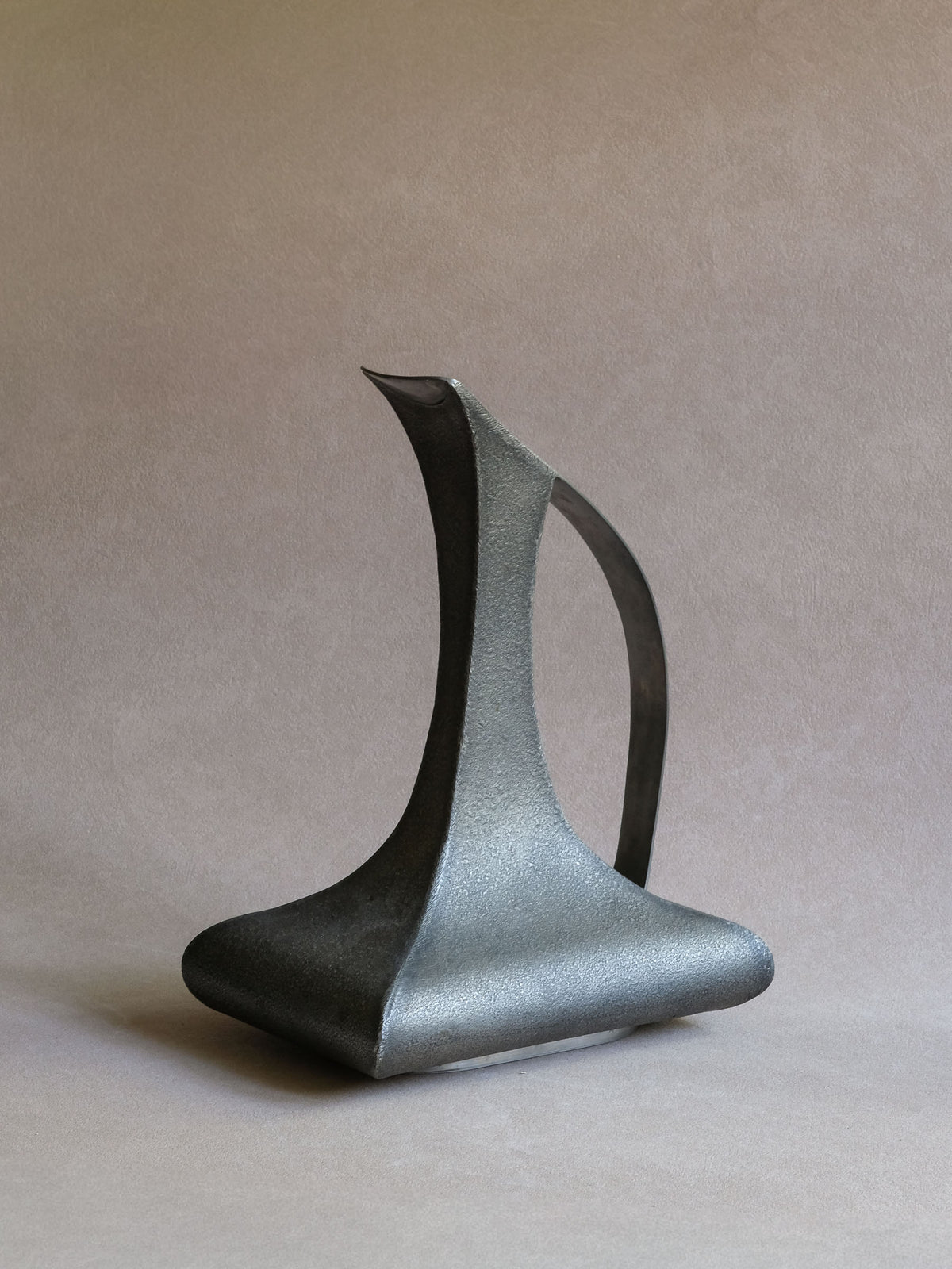 Large Italian pewter decanter-form vase, three-quarter view showing tall sculptural neck, handle and broad base.