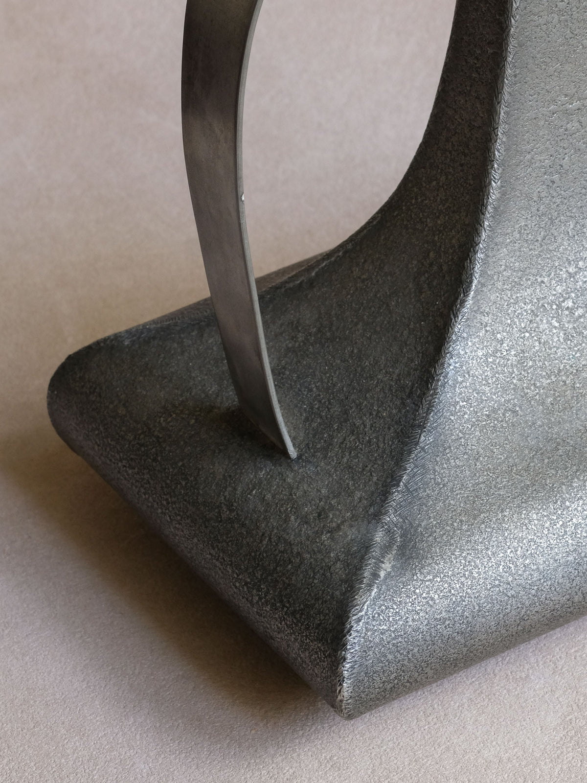 Close-up of the broad lower body and angular corner on the large Italian pewter sculptural vessel.