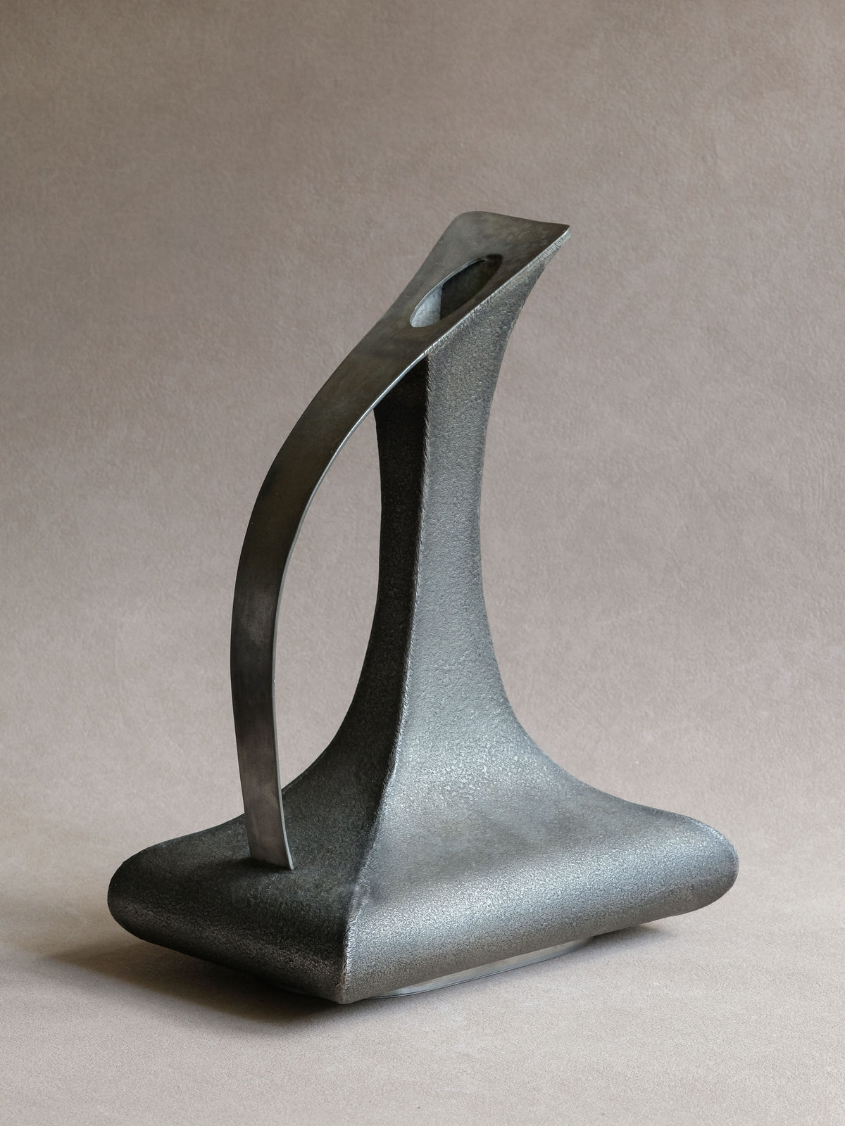 Rear three-quarter view of large Italian pewter vase showing sweeping handle and architectural profile.