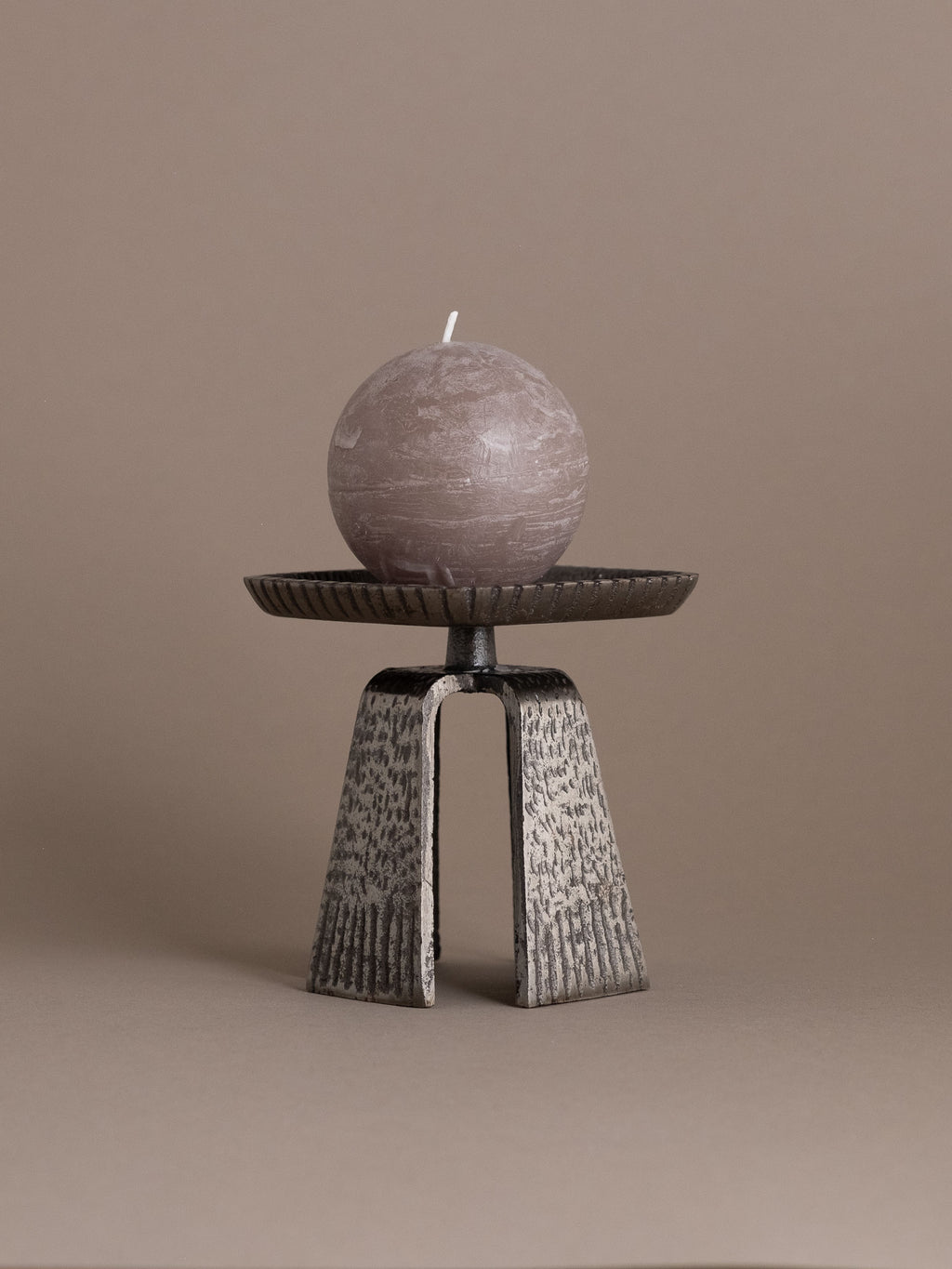 Cast iron pricket candle holder shown holding a round candle, with the square tray and central spike partially visible.