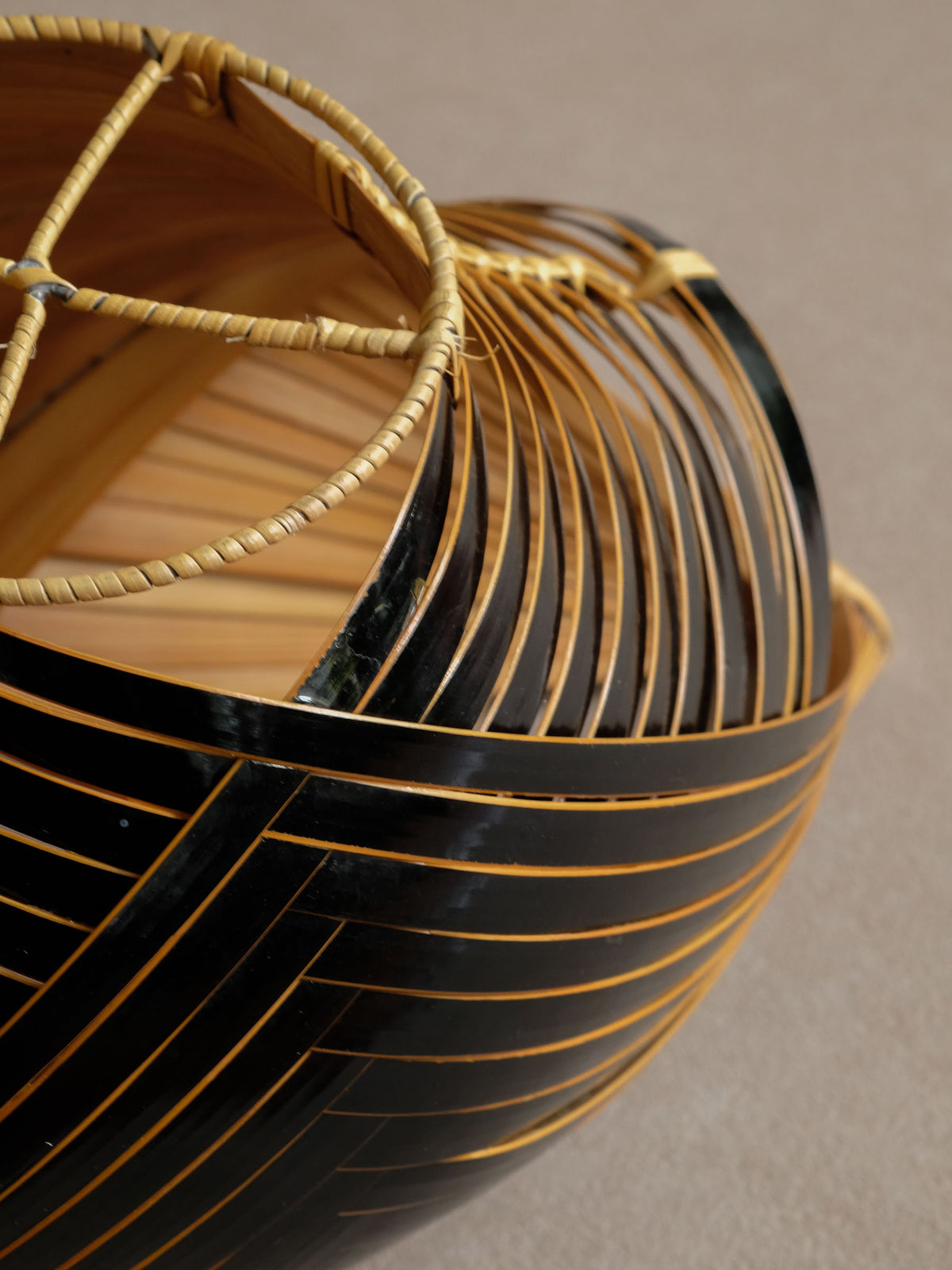 Looking inside the dark bamboo basket to show layered bamboo weaving around the central opening.