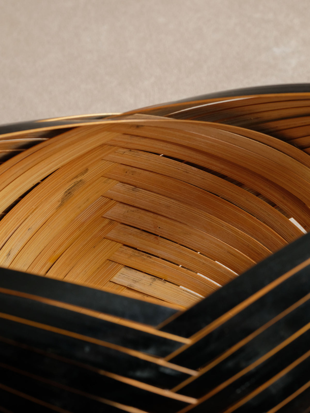 Close-up of naturally coloured inner bamboo woven beneath black curved outer strips.