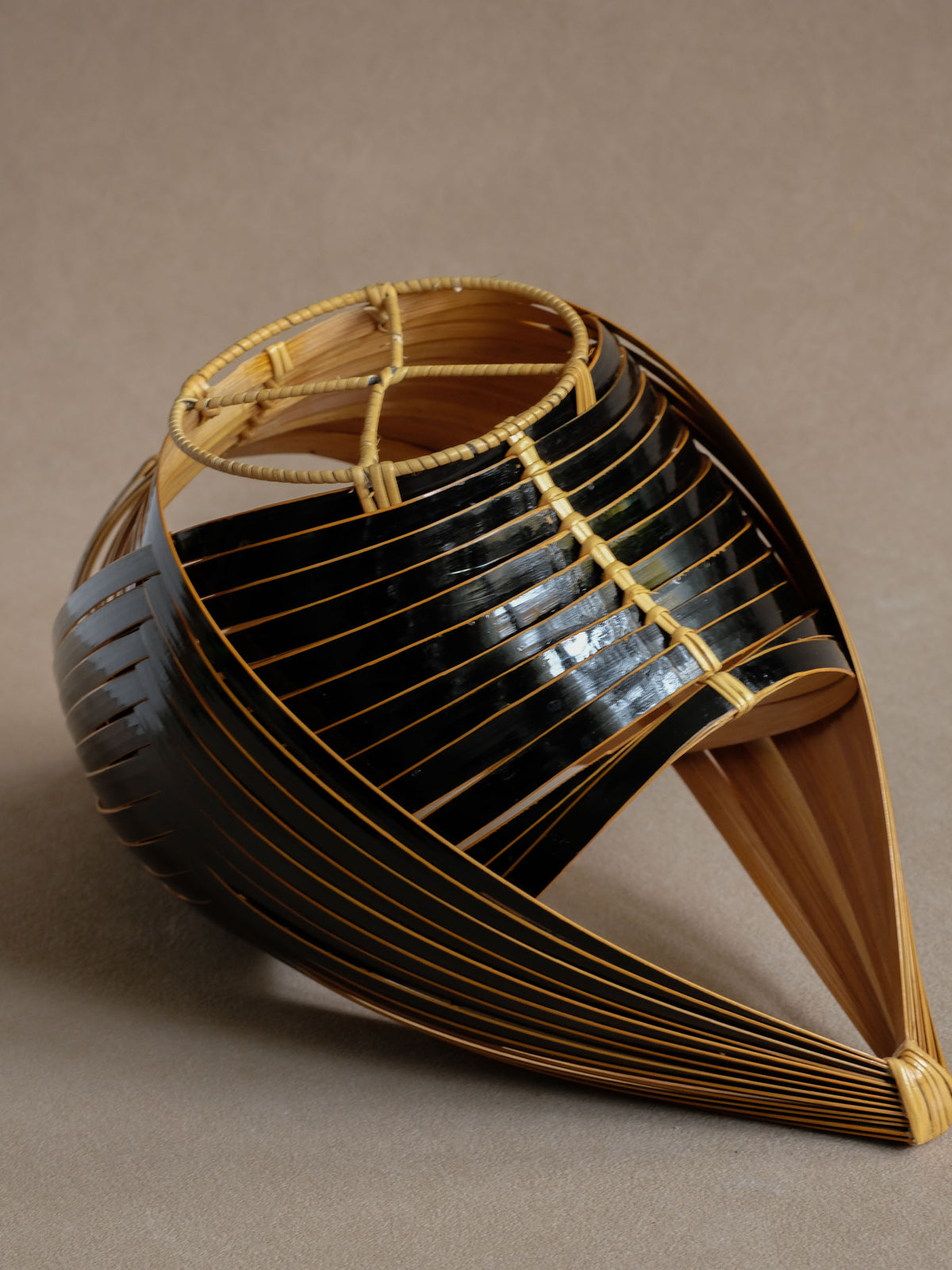 Underside view of dark woven bamboo basket showing bamboo support and open construction.