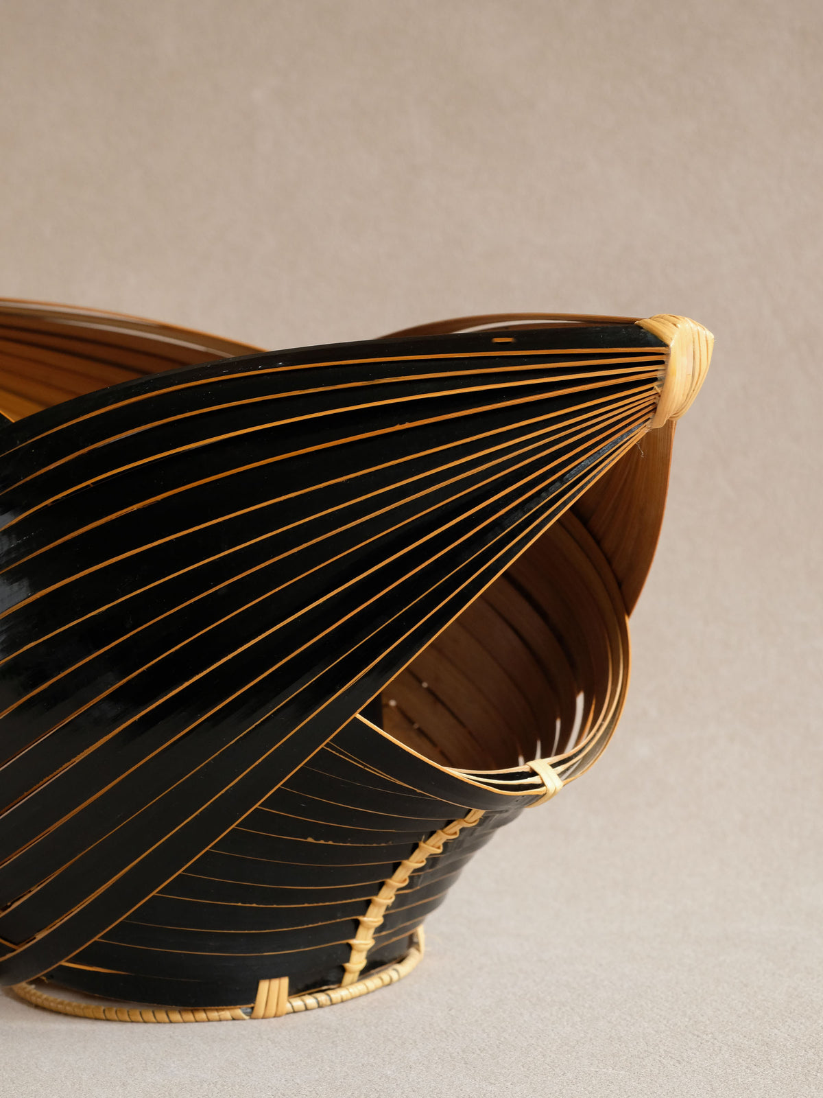 Close-up of the black and natural bamboo strips meeting at the base of a layered woven panel.