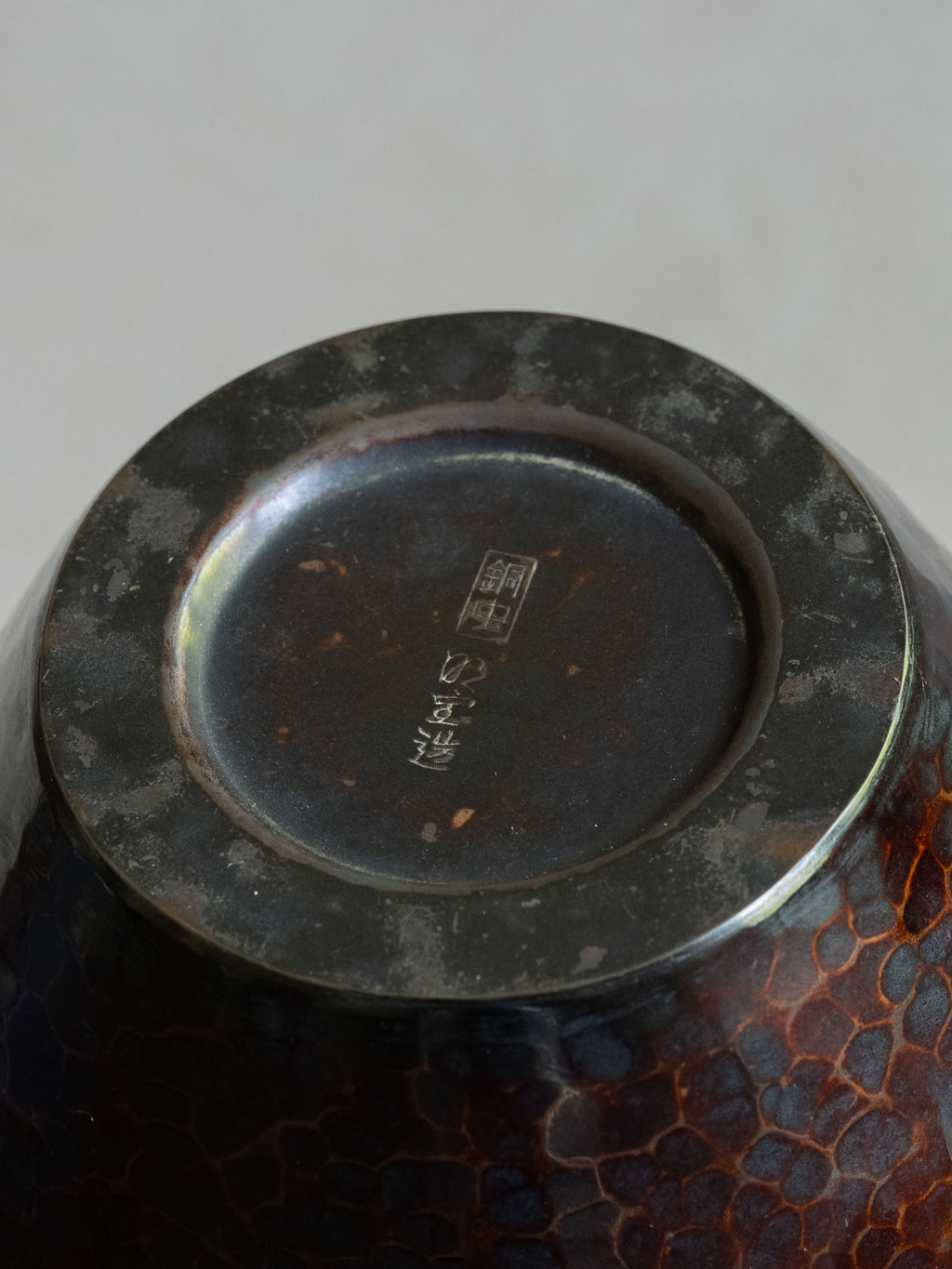 Underside of Japanese Dochu copper vase showing base mark and dark patinated metal surface.
