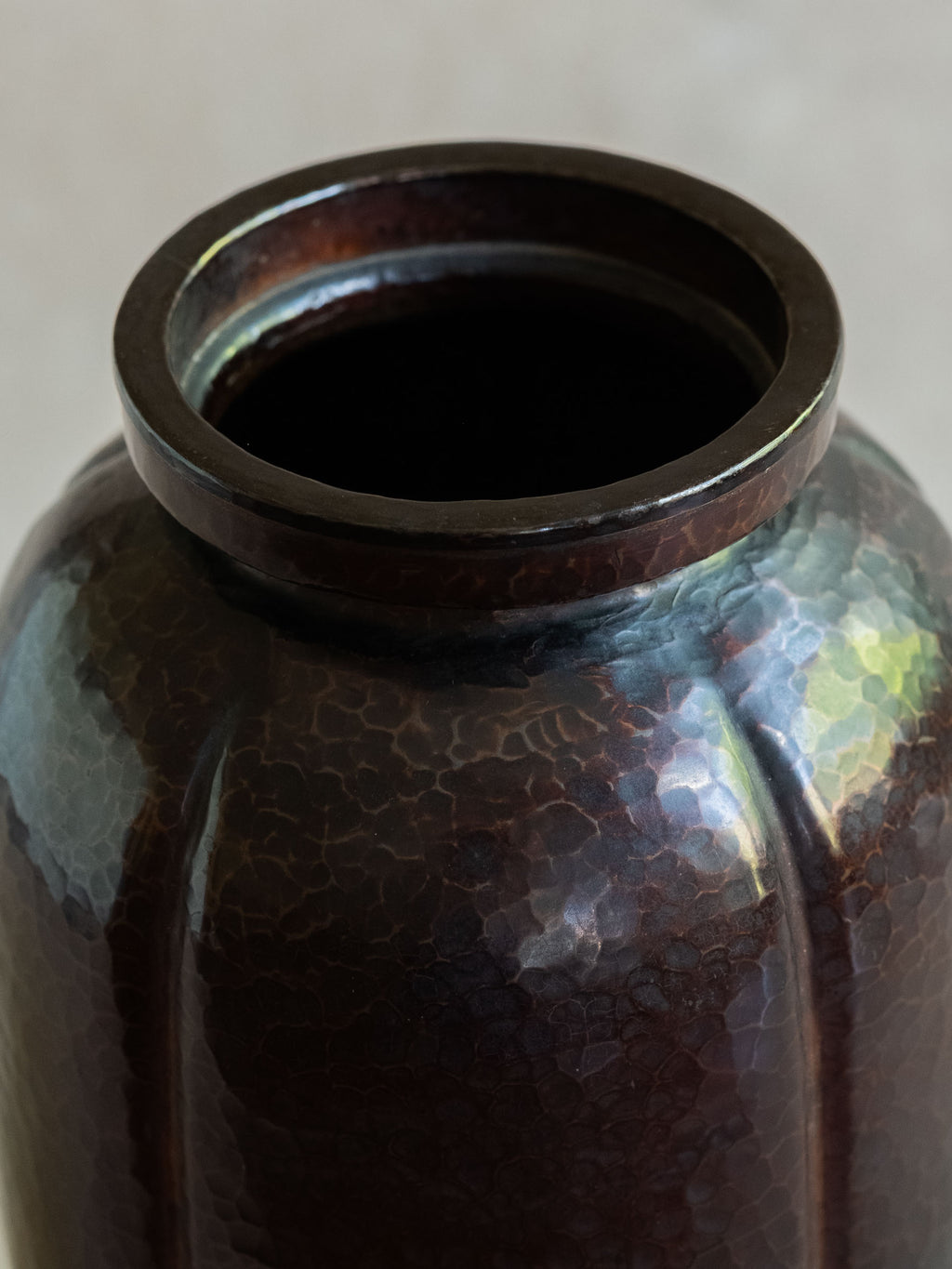 Close-up of the mouth and shoulder of a Japanese Dochu copper vase with ribbed body and hammered patina.
