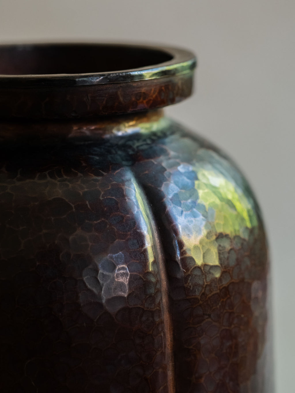 Detail of Japanese Dochu copper vase showing raised vertical rib and hammered dark patinated surface.
