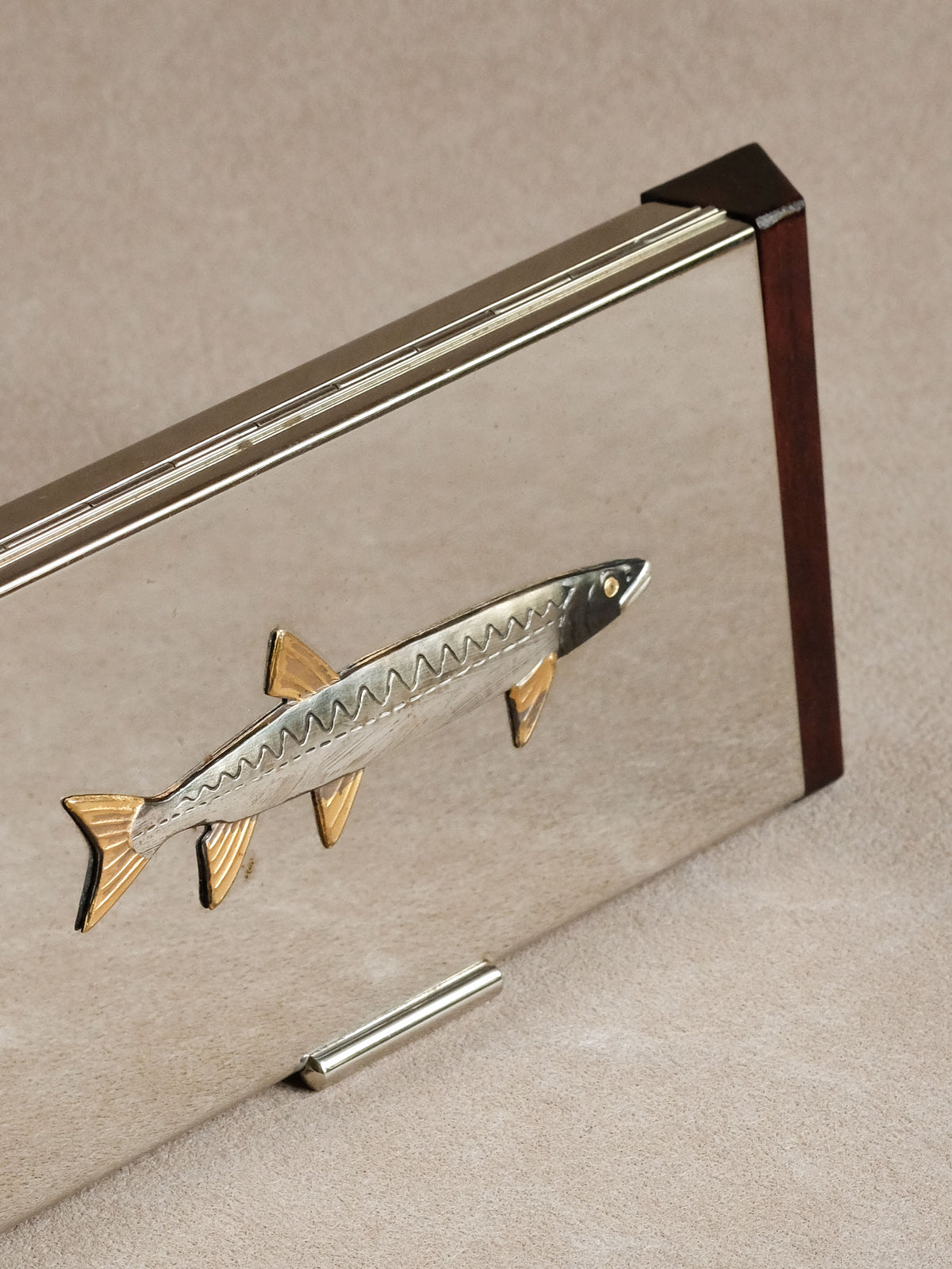 Detail photograph of the fish-shaped metal ornament on a Japanese wooden tray.