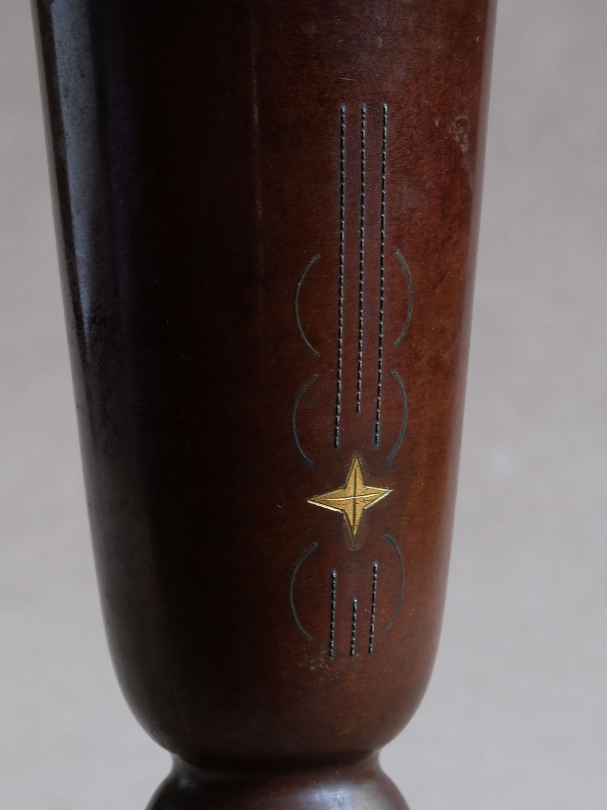 Close-up of zōgan inlay on Japanese cast copper vase, with gold-coloured star and fine linear metal decoration.
