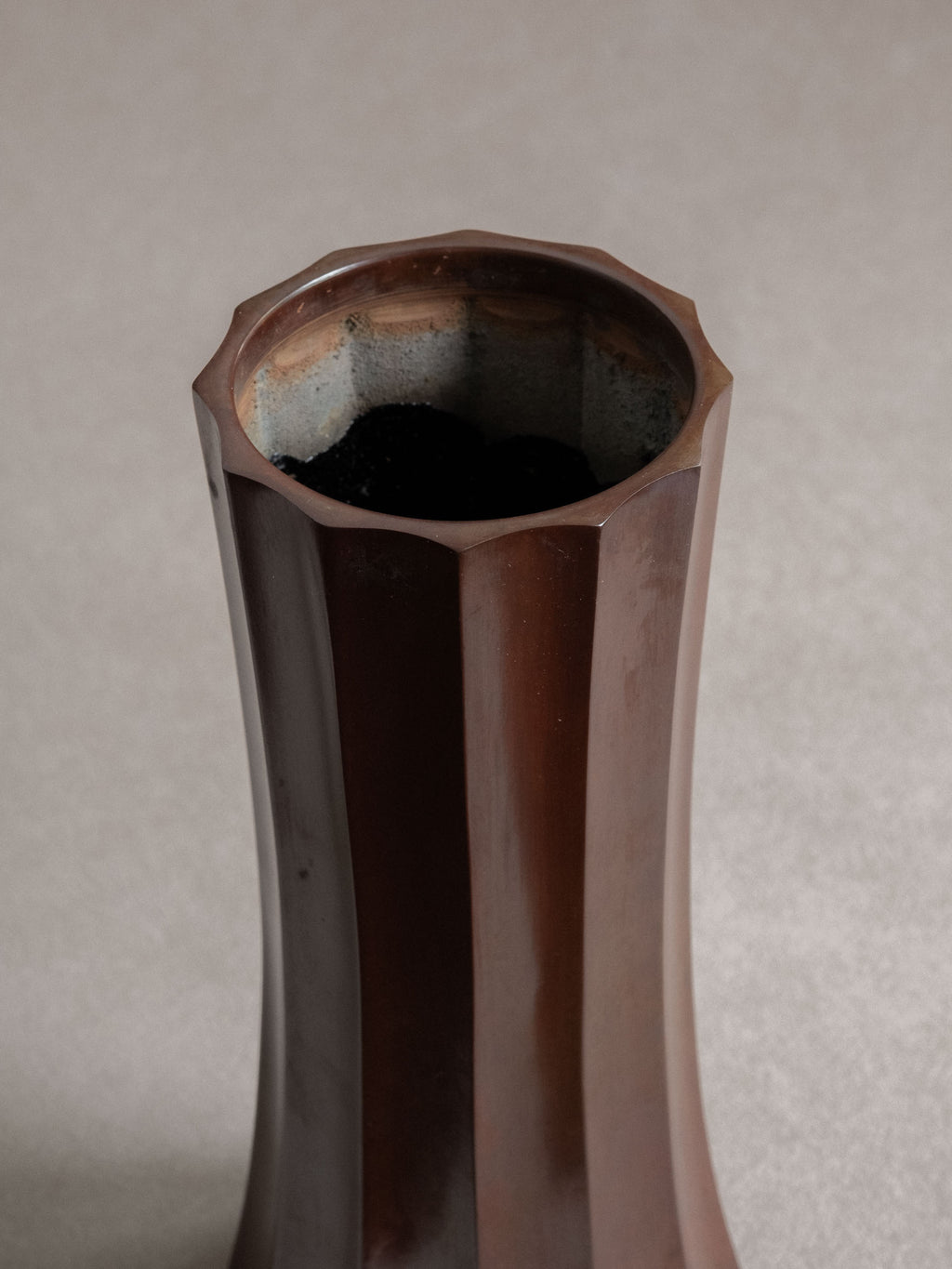 Close-up of the open rim and oxidised interior of a Japanese Takaoka cast copper faceted vase.