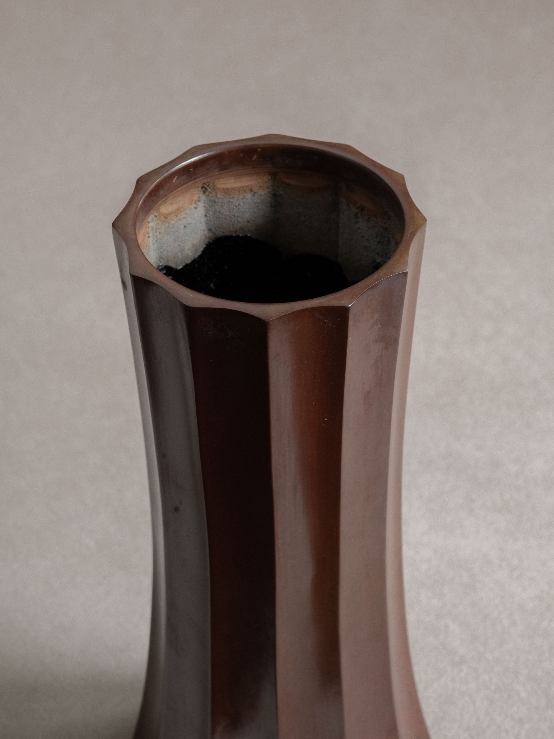 Close-up of the open rim and oxidised interior of a Japanese Takaoka cast copper faceted vase.