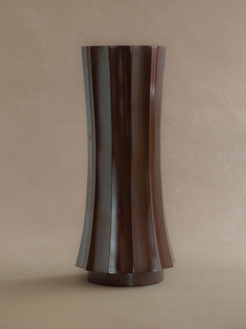 Front view of a tall Japanese Takaoka cast copper vase with faceted body, open mouth, and dark patina.
