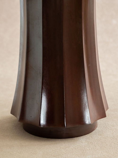 Close-up of the lower faceted body of a dark reddish-brown Takaoka cast copper vase.
