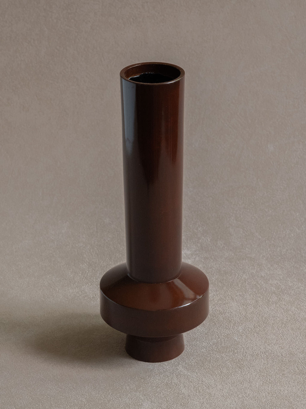 Close-up view of a Japanese copper-alloy single-flower vase with tall cylindrical neck, narrow mouth, and stepped circular base.
