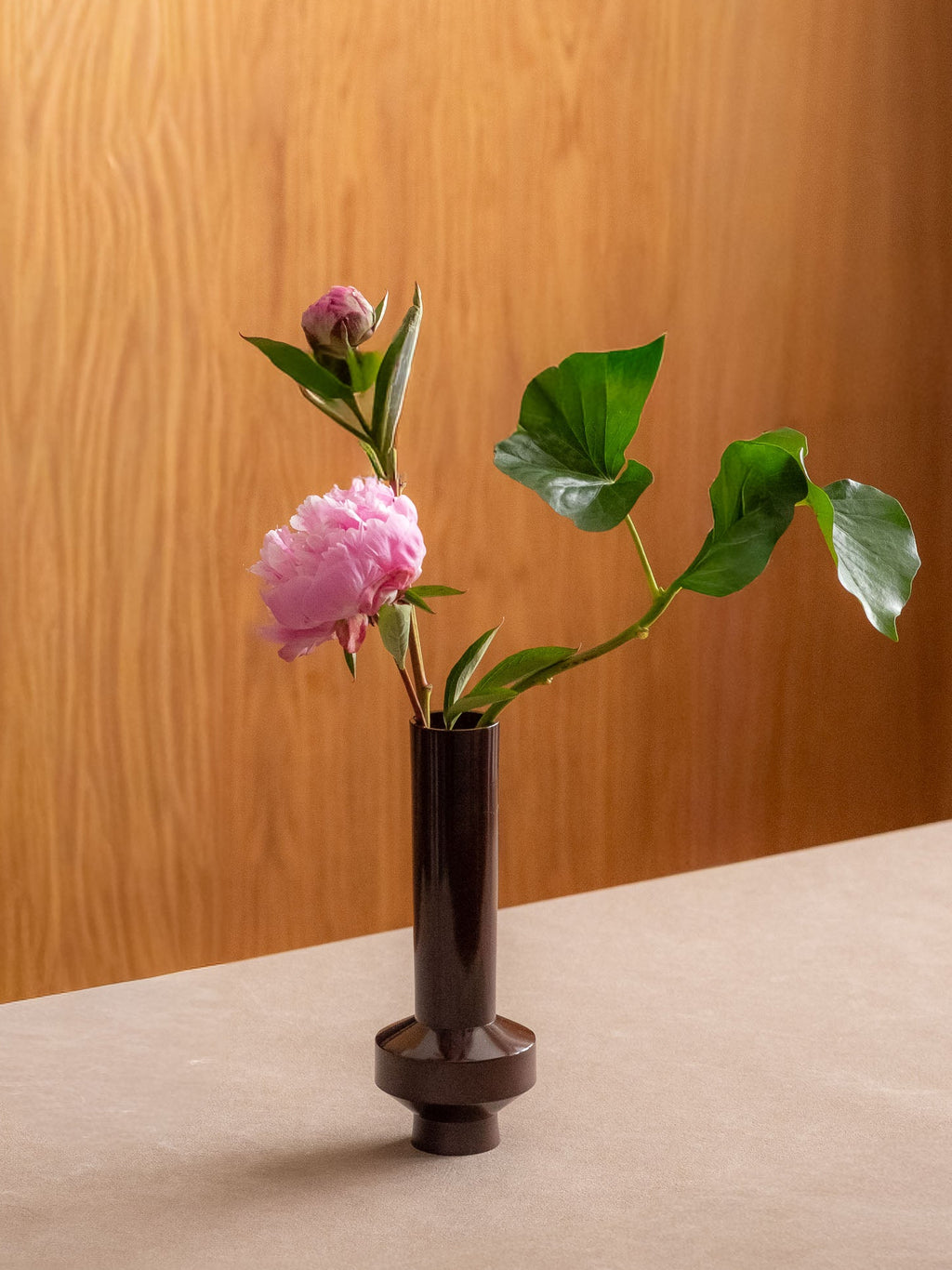 Japanese single-flower vase displayed with a small pink flower arrangement on a tabletop.