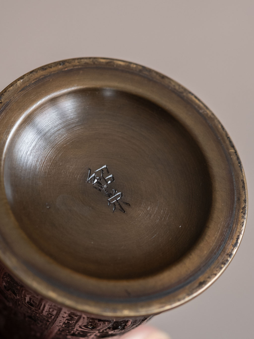 Interior base of a Japanese bronze flower vase showing the incised maker’s mark 紹栄 on the underside.