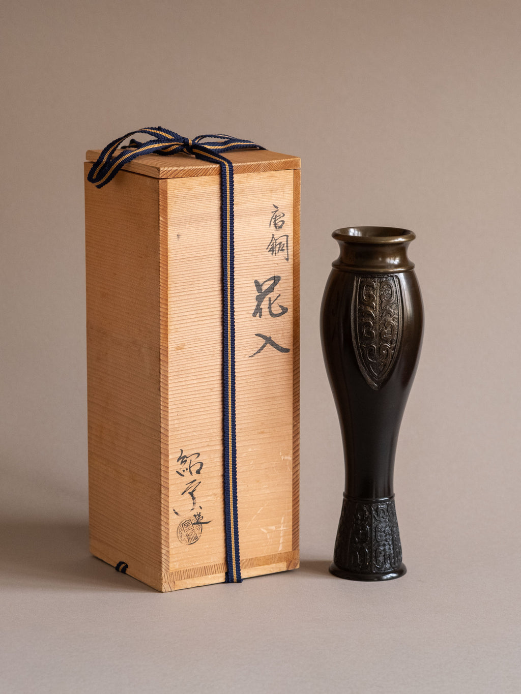Japanese bronze flower vase by Kanamori Shōei shown beside its original signed wooden storage box with Japanese calligraphy and seal.