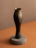 Three-quarter view of a Japanese bronze flower vase by Kanamori Shōei with rolled rim, dark patina, and cast relief decoration.