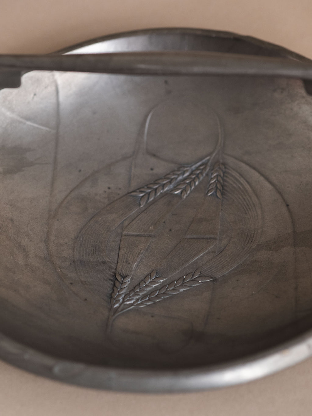 Interior detail of Kayserzinn pewter bowl showing triangular relief field with stylised wheat motif.