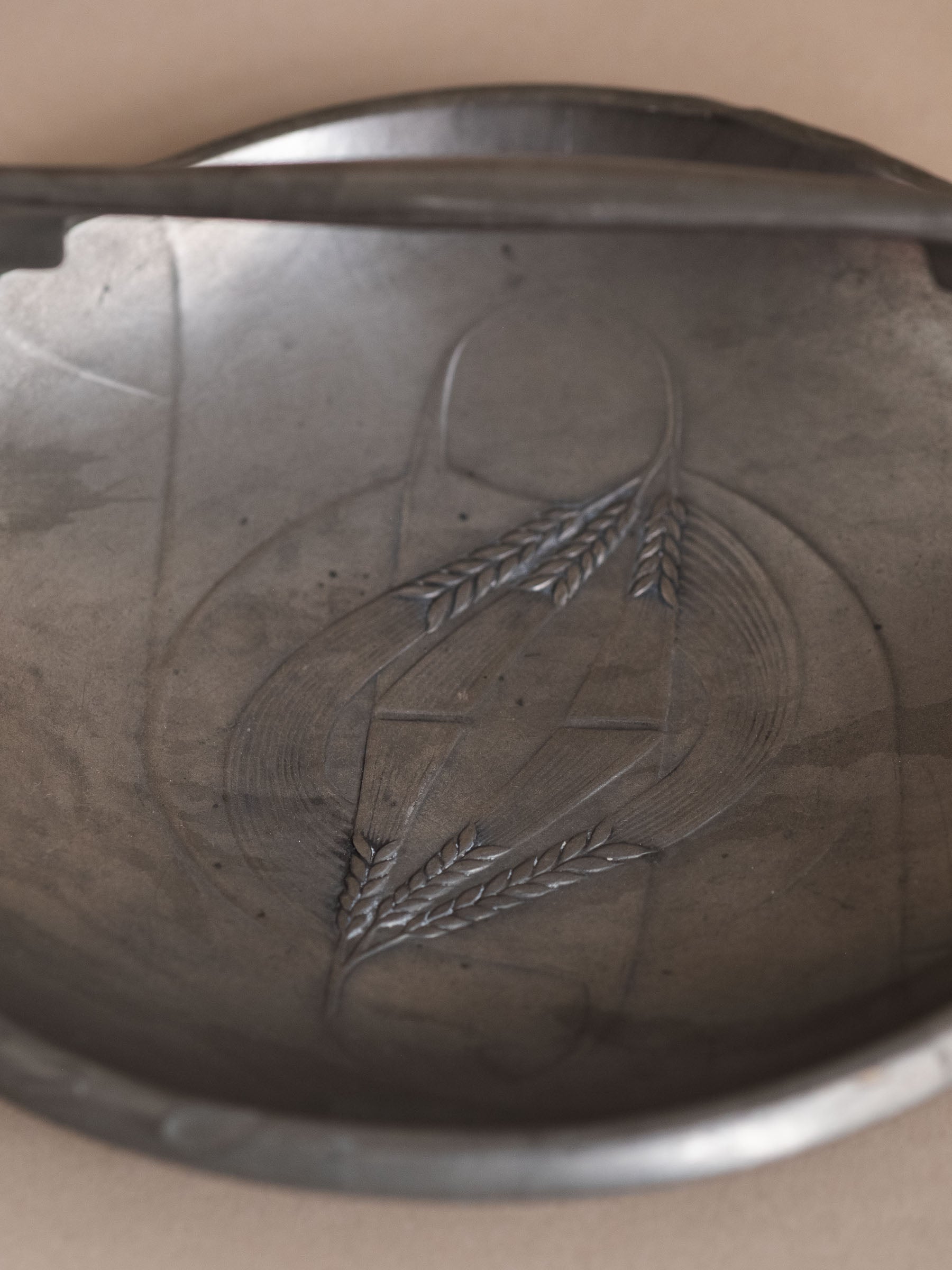 Interior detail of Kayserzinn pewter bowl showing triangular relief field with stylised wheat motif.