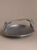 Kayserzinn pewter handled bowl with arched integrated handle and shallow circular basin, photographed against a neutral brown background.